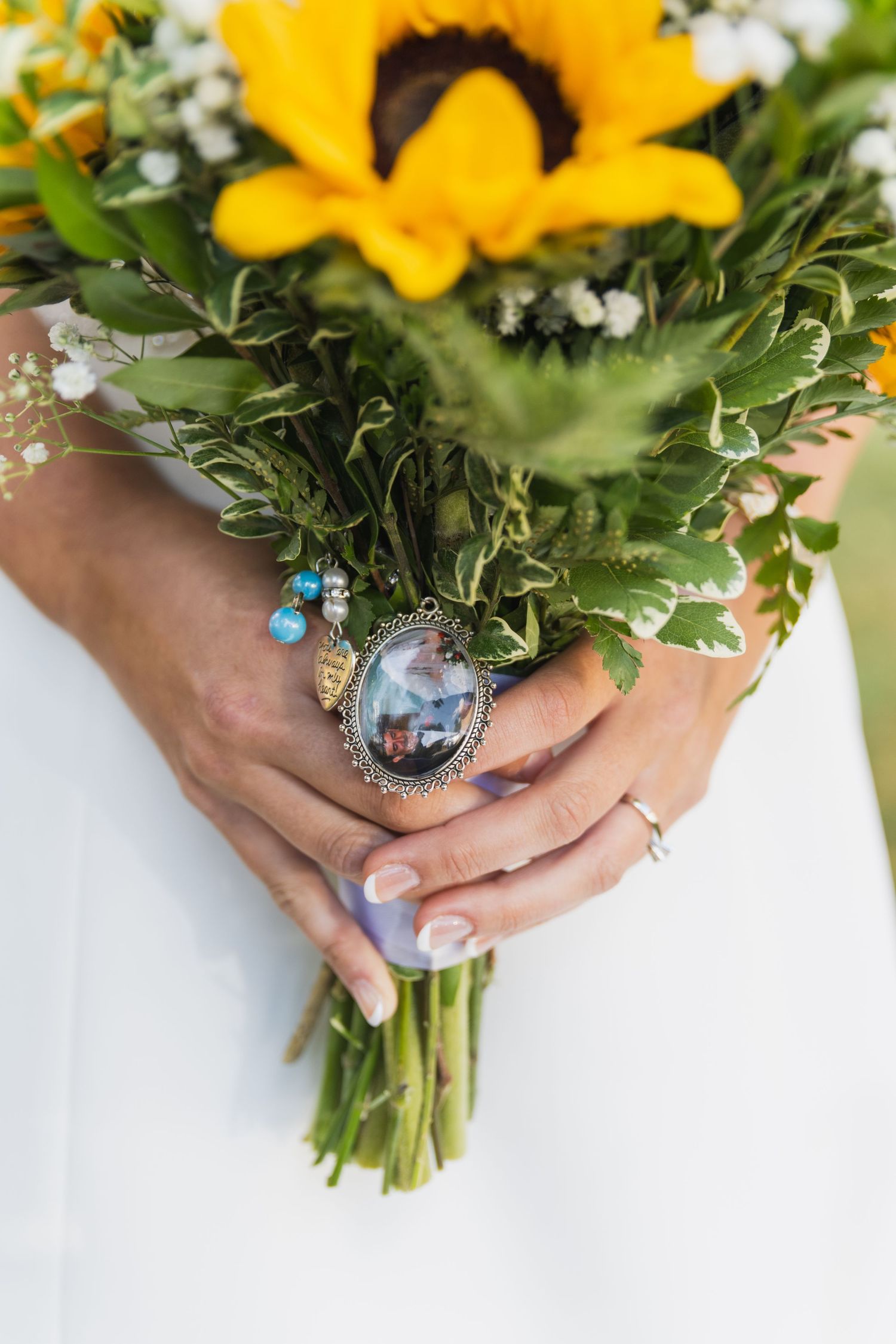 Close up of sunflower bouquet with vintage photo lockets attached.