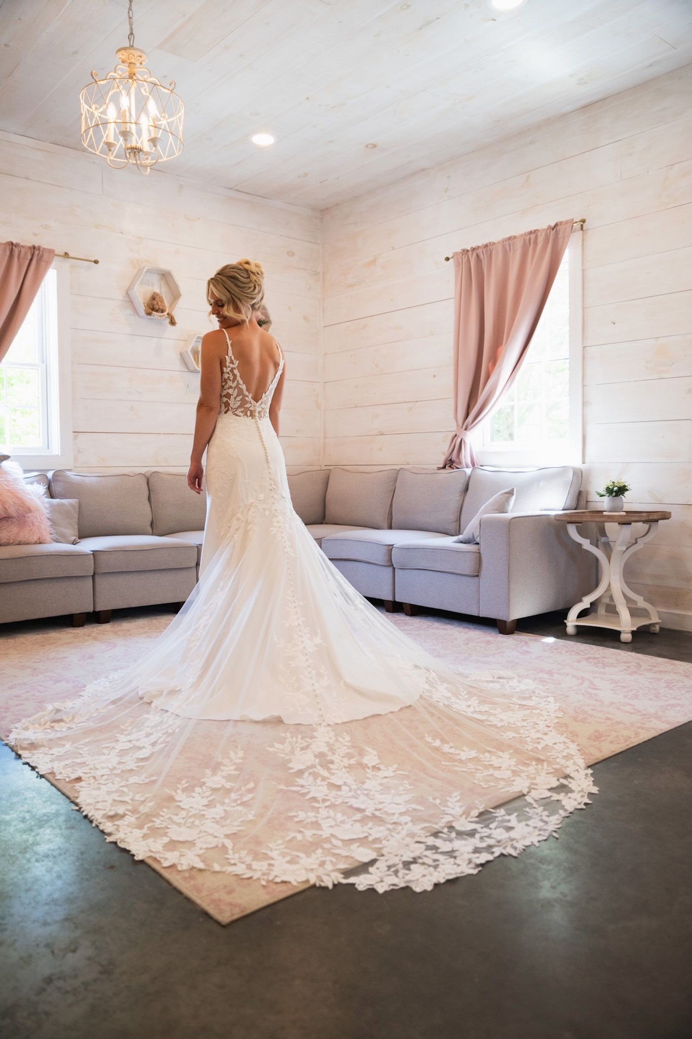 Elegant bridal gown with dramatic cathedral train displayed in white room.