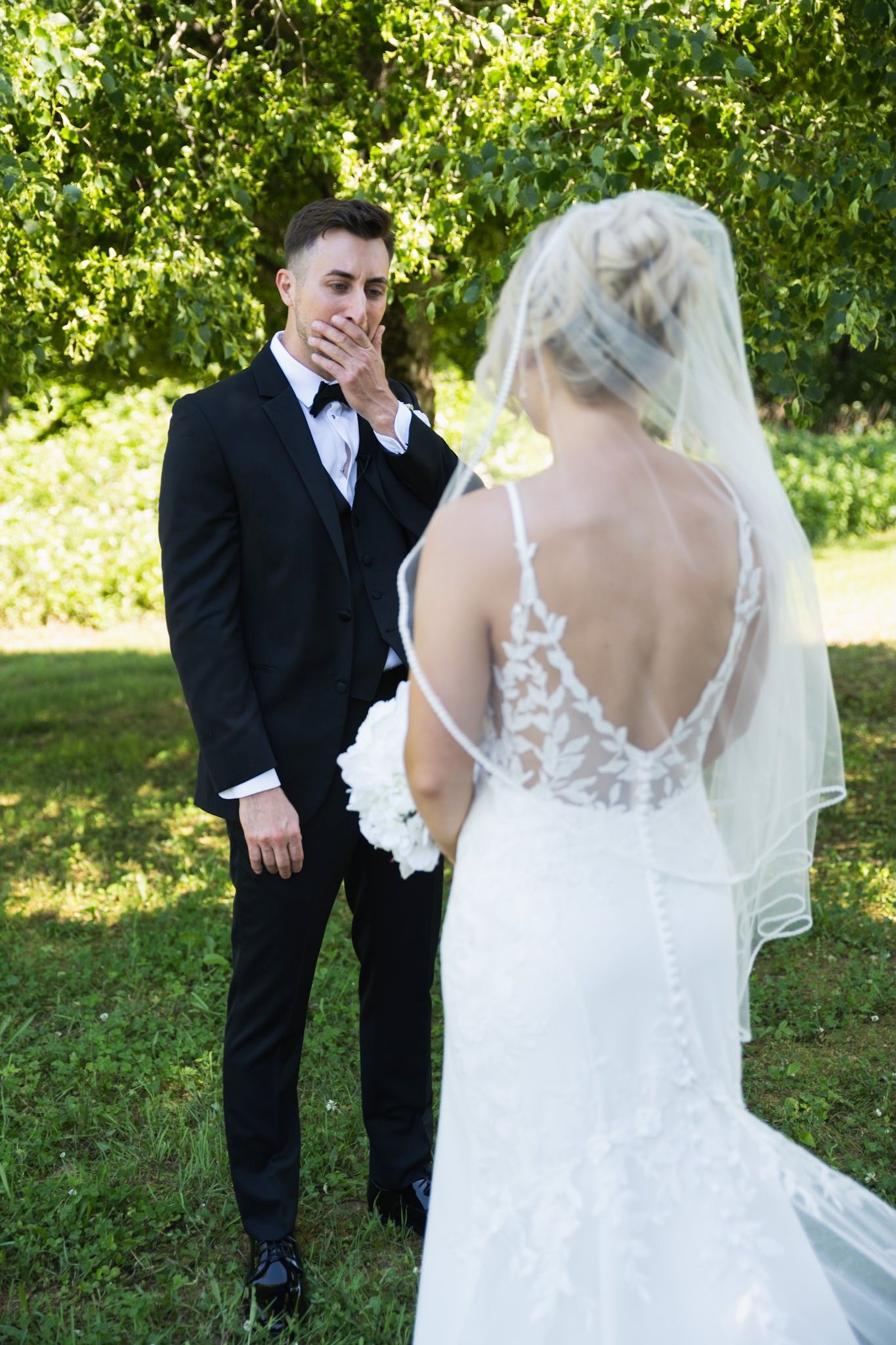 Emotional first look sequence between bride and groom in a lush green garden.