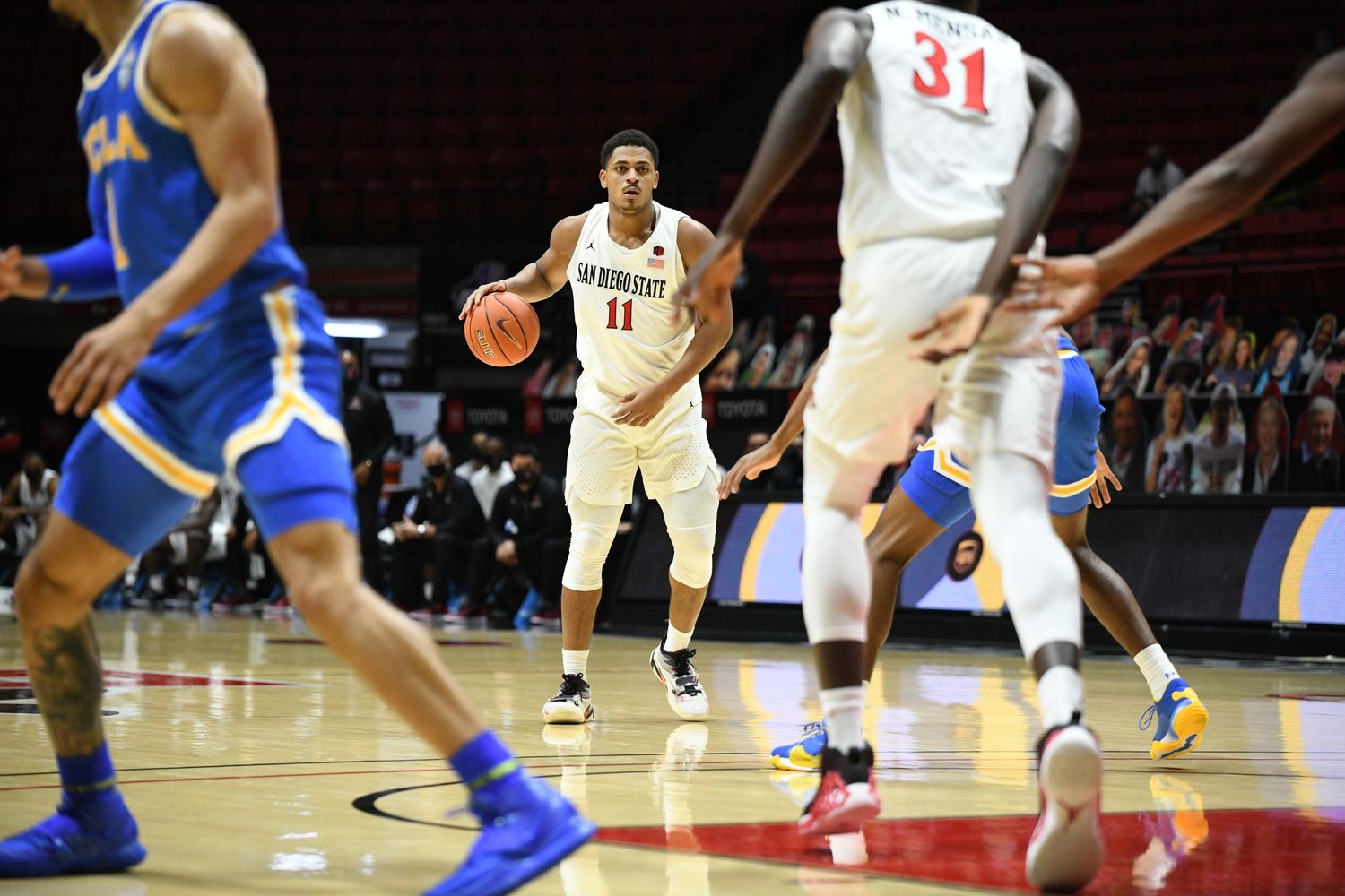 San Diego State basketball player number 11 dribbles ball during NCAA college basketball game.