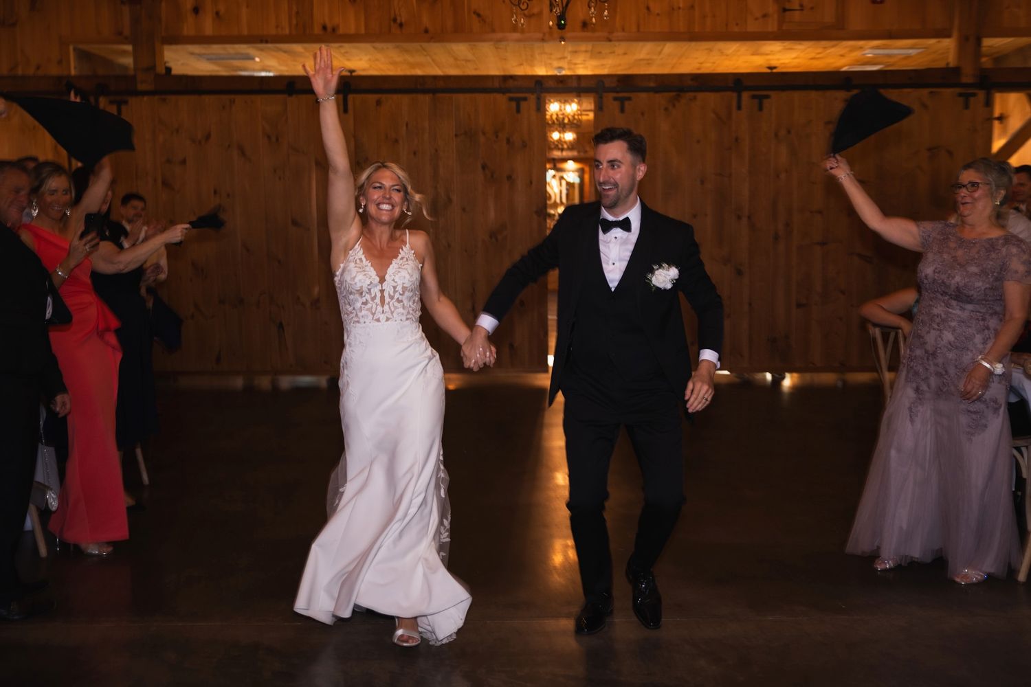 Wedding couple dancing in elegant attire at rustic barn venue.