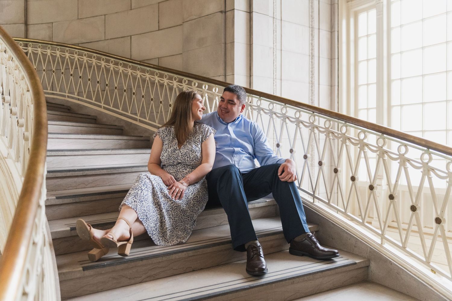 Couple sitting and relaxing on elegant marble staircase in historic building.