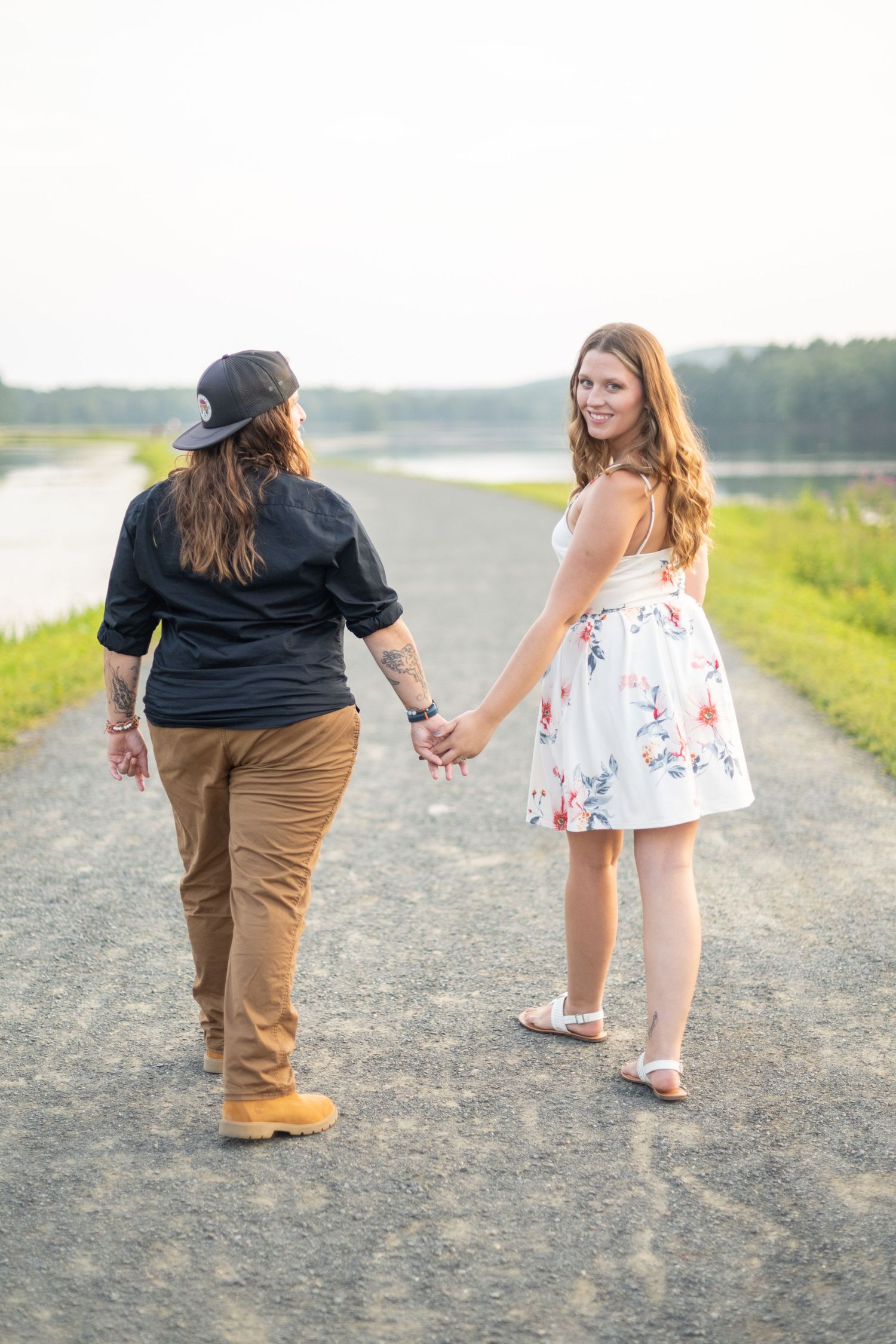 Couple walking hand in hand along a dirt path during golden hour.