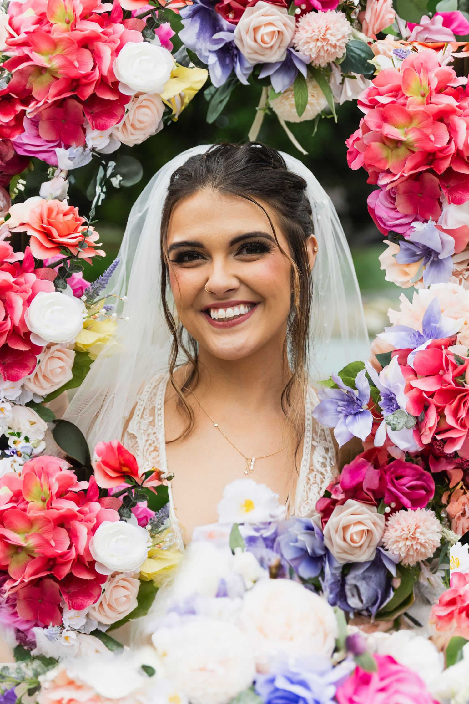 Colorful floral arch with vibrant pink, purple, and white blooms creates a stunning wedding backdrop.