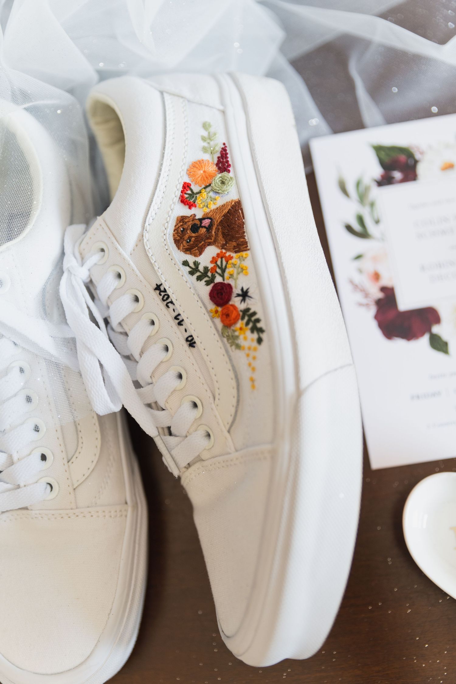 Close-up of white sneakers with delicate floral embroidery details.