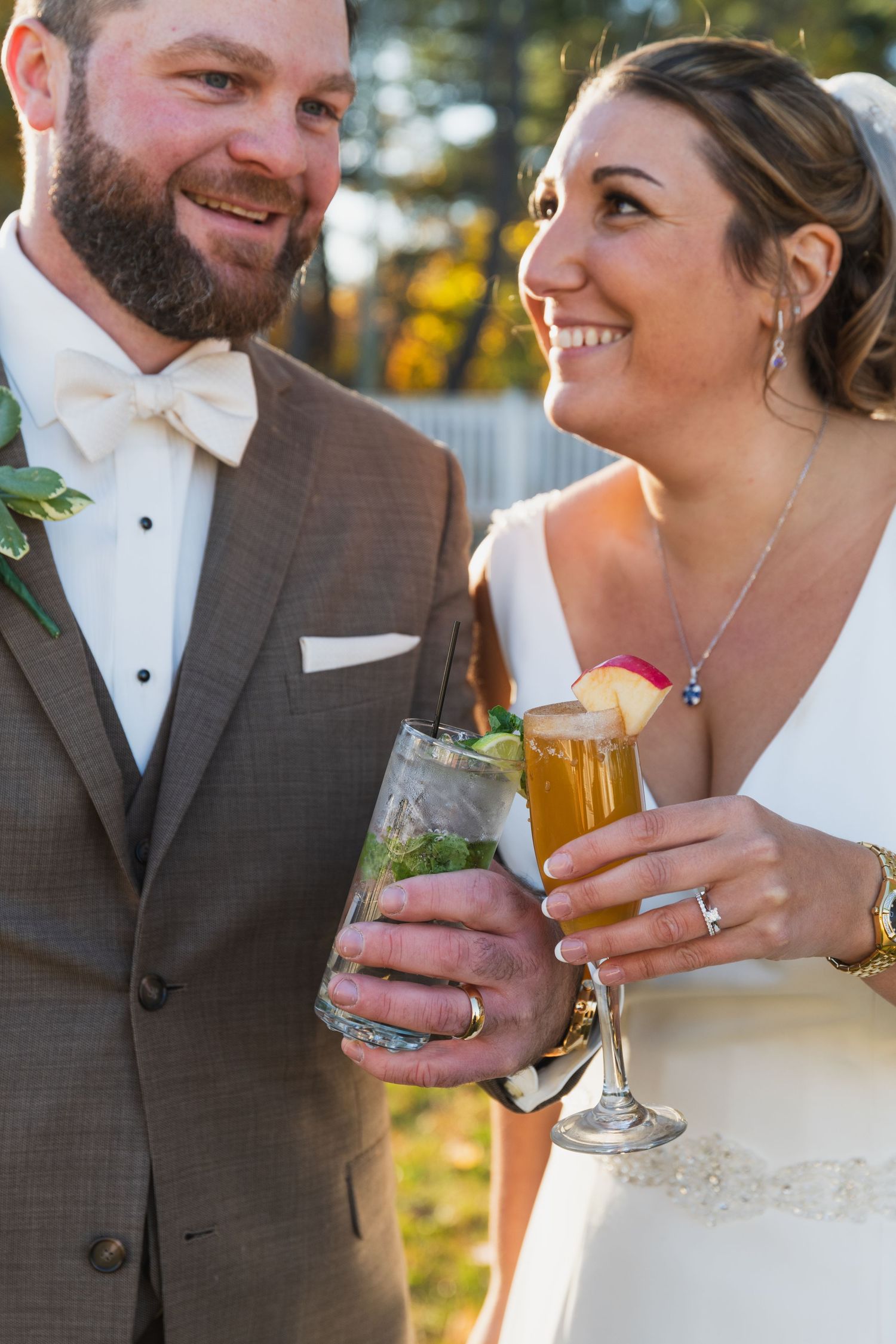 Wedding couple sharing drinks and smiles during sunset at their reception celebration.