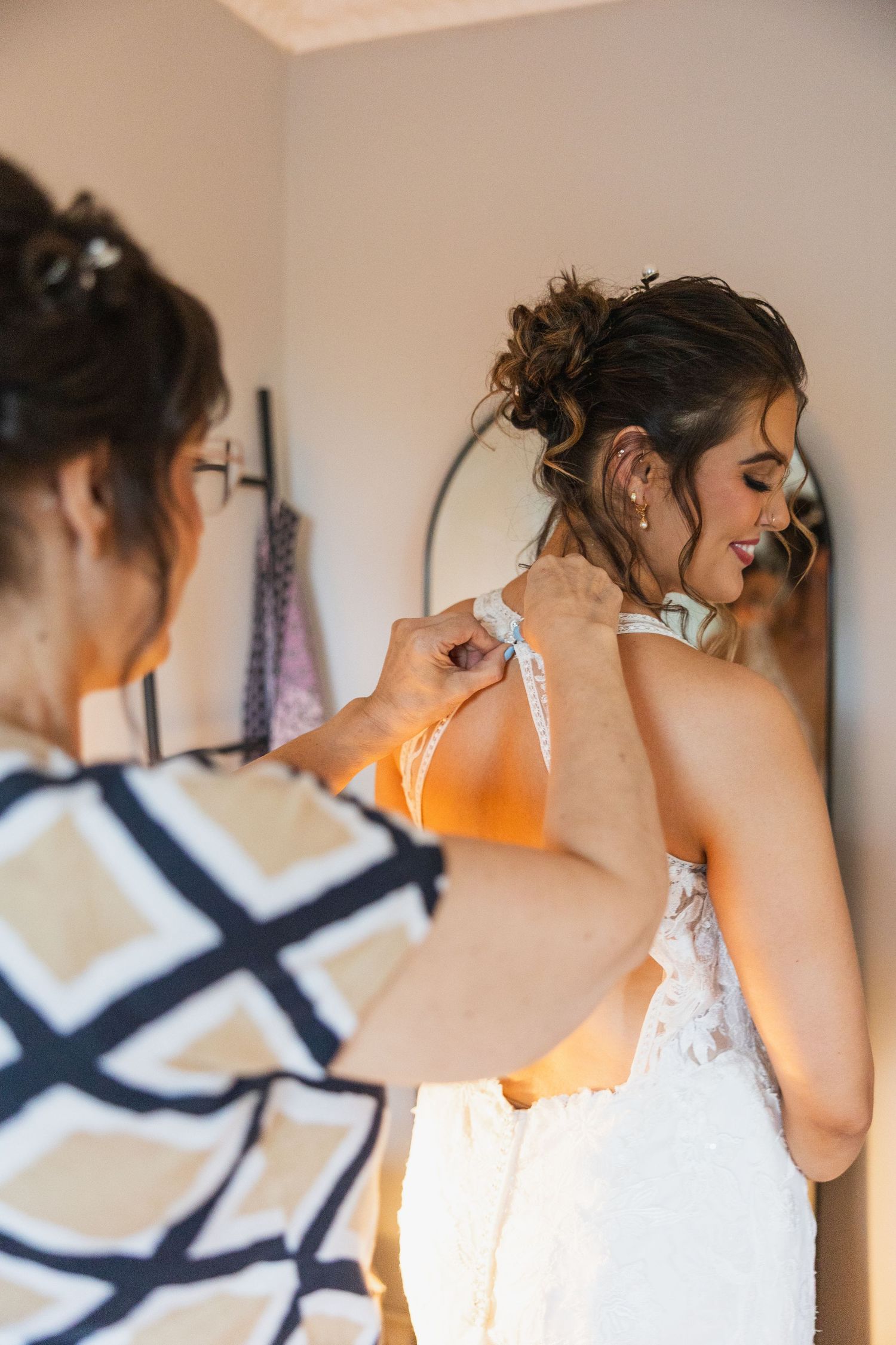 Close-up of intricate lace details on a wedding dress against a neutral wall.