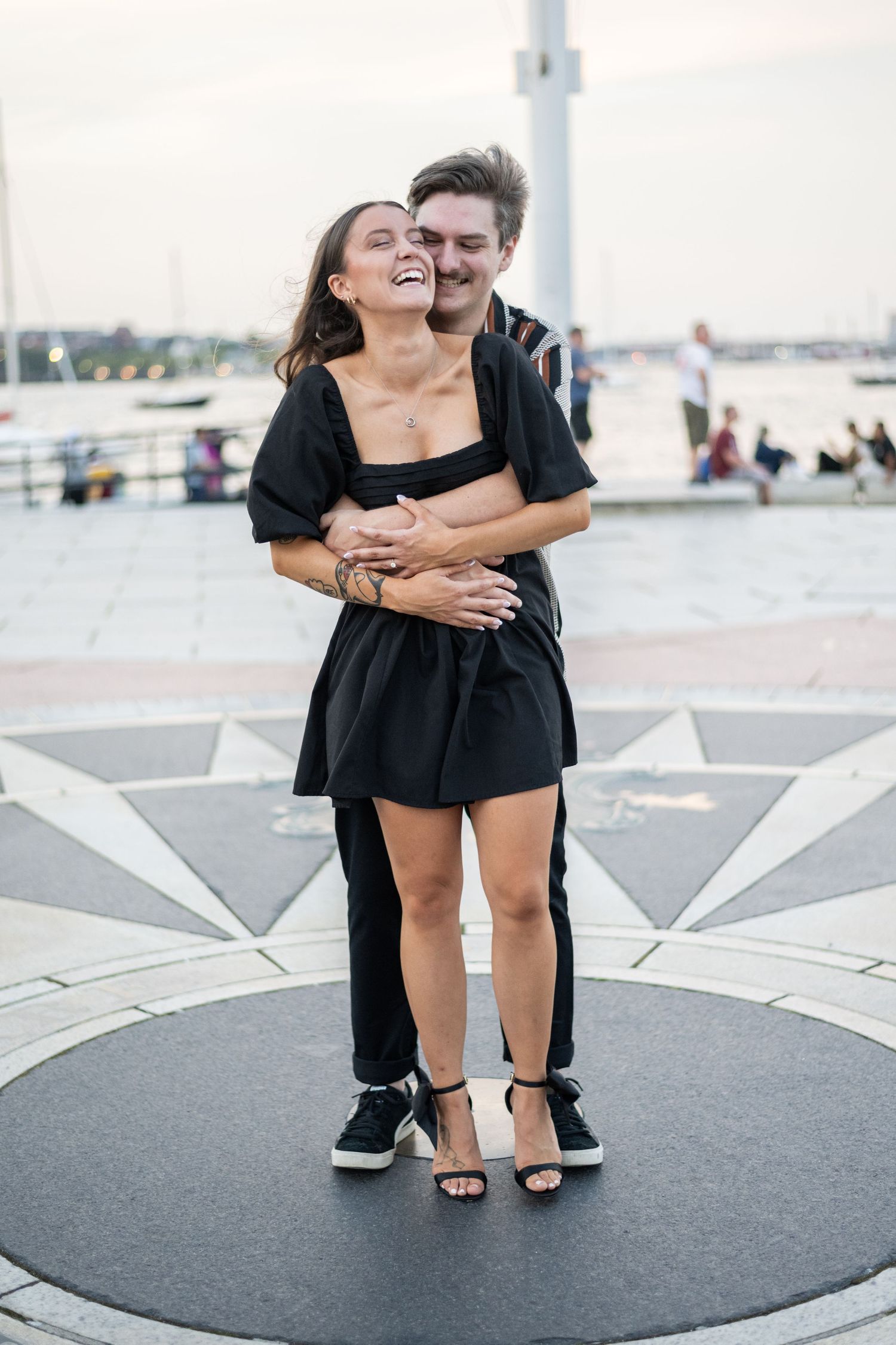 Playful couple shares intimate moments on a waterfront boardwalk.