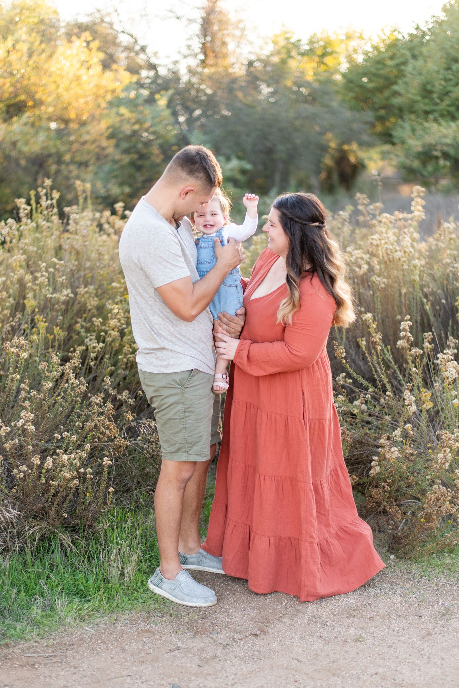 Family sharing a tender moment together on a nature path at golden hour.