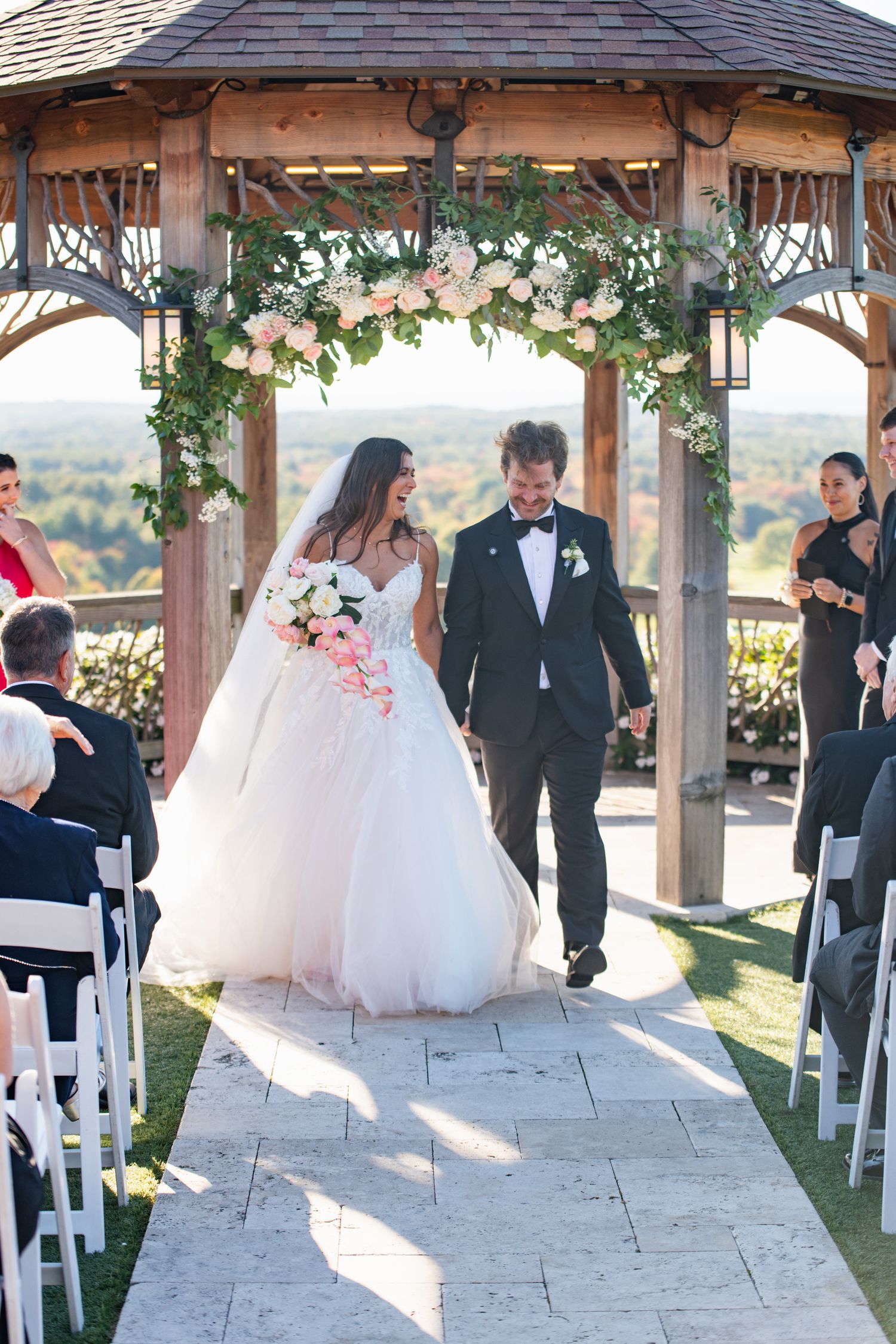 A sequence of wedding ceremony photos showing a couple walking down an outdoor stone aisle under a wooden gazebo.