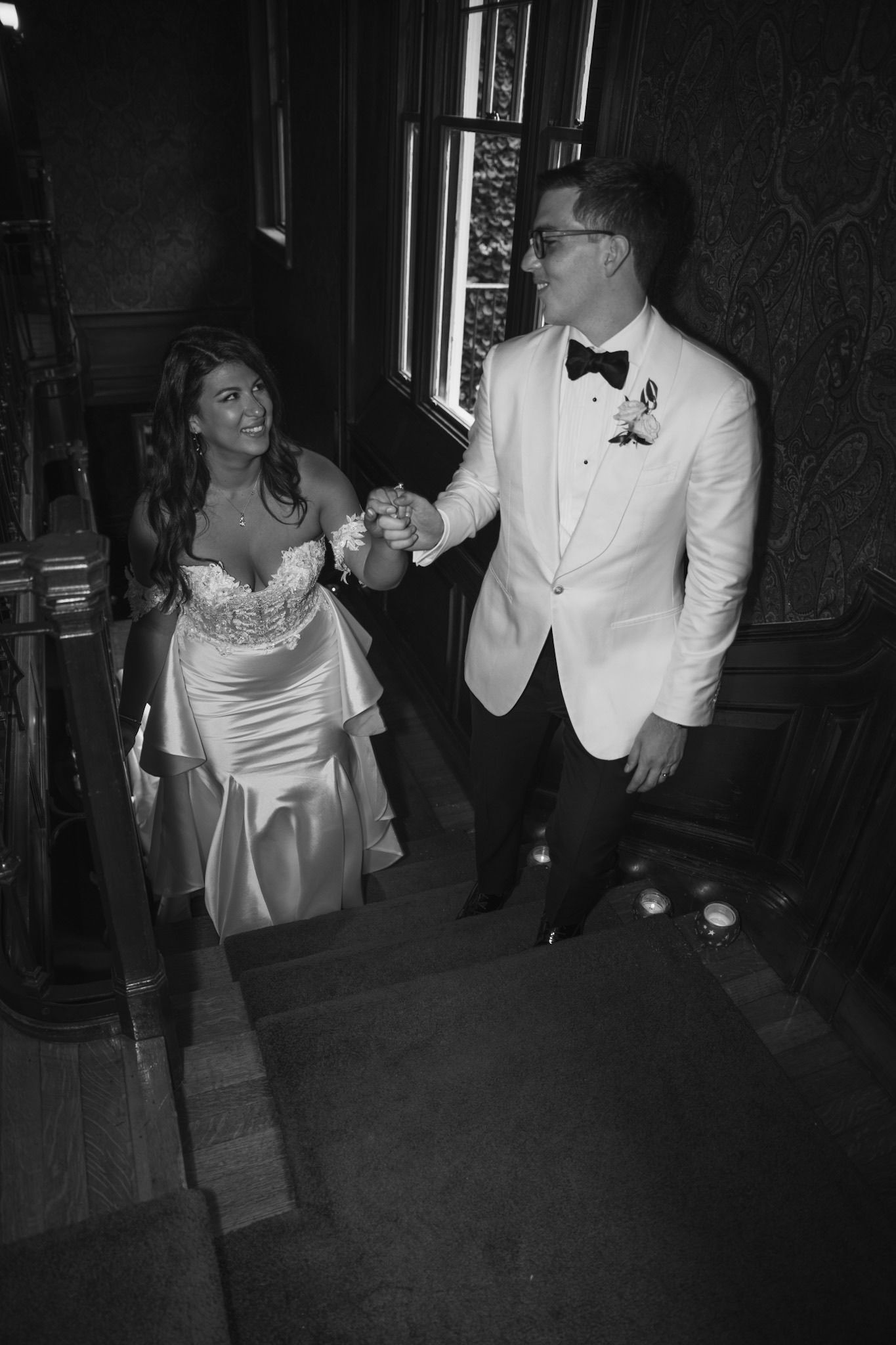 Black and white reception photo shows wedding party dancing in formal attire.
