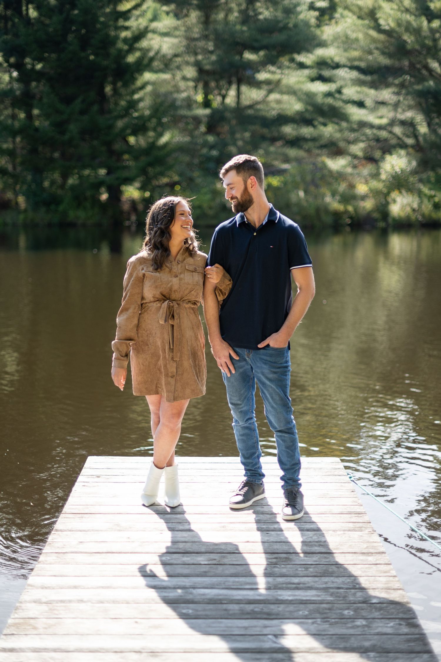 Couple sharing intimate moments on a dock overlooking a serene lake.
