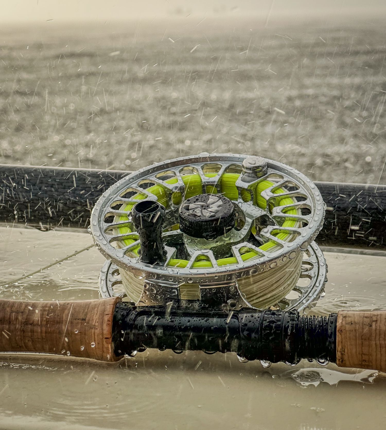 Fly reel on a skiff with rain drops bouncing on and around it.
