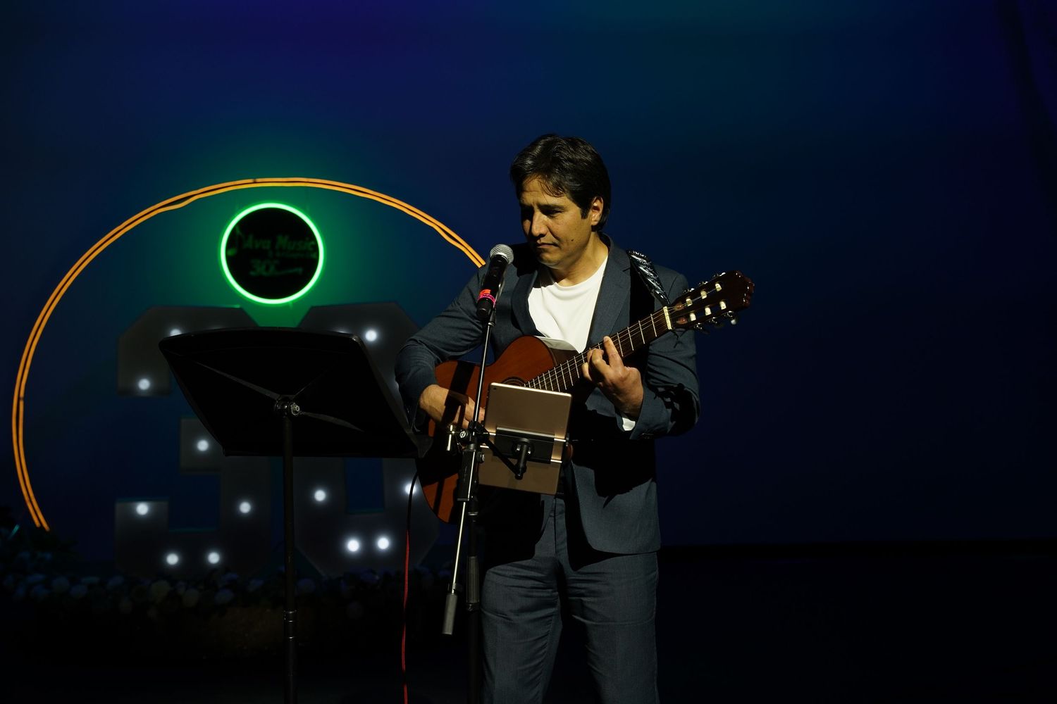 Male guitarist performing on stage with glowing circular light installation backdrop.