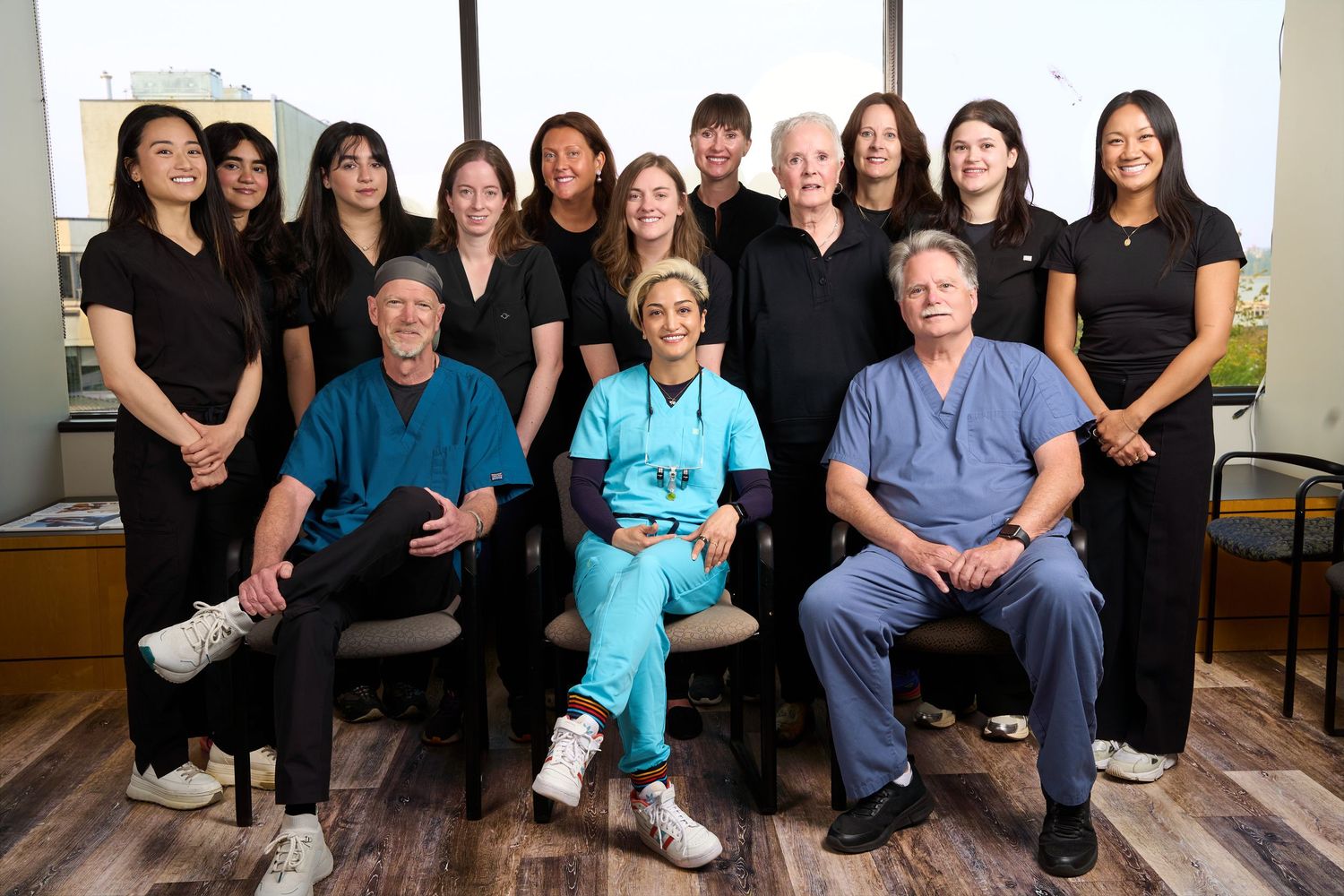 Medical team of doctors and staff posing together in a professional clinic setting, wearing scrubs and uniforms.