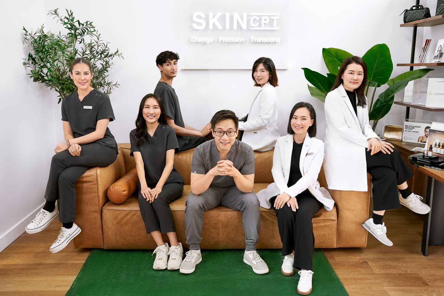 Team of seven skincare professionals posing together inside a modern SkinOpt beauty clinic.