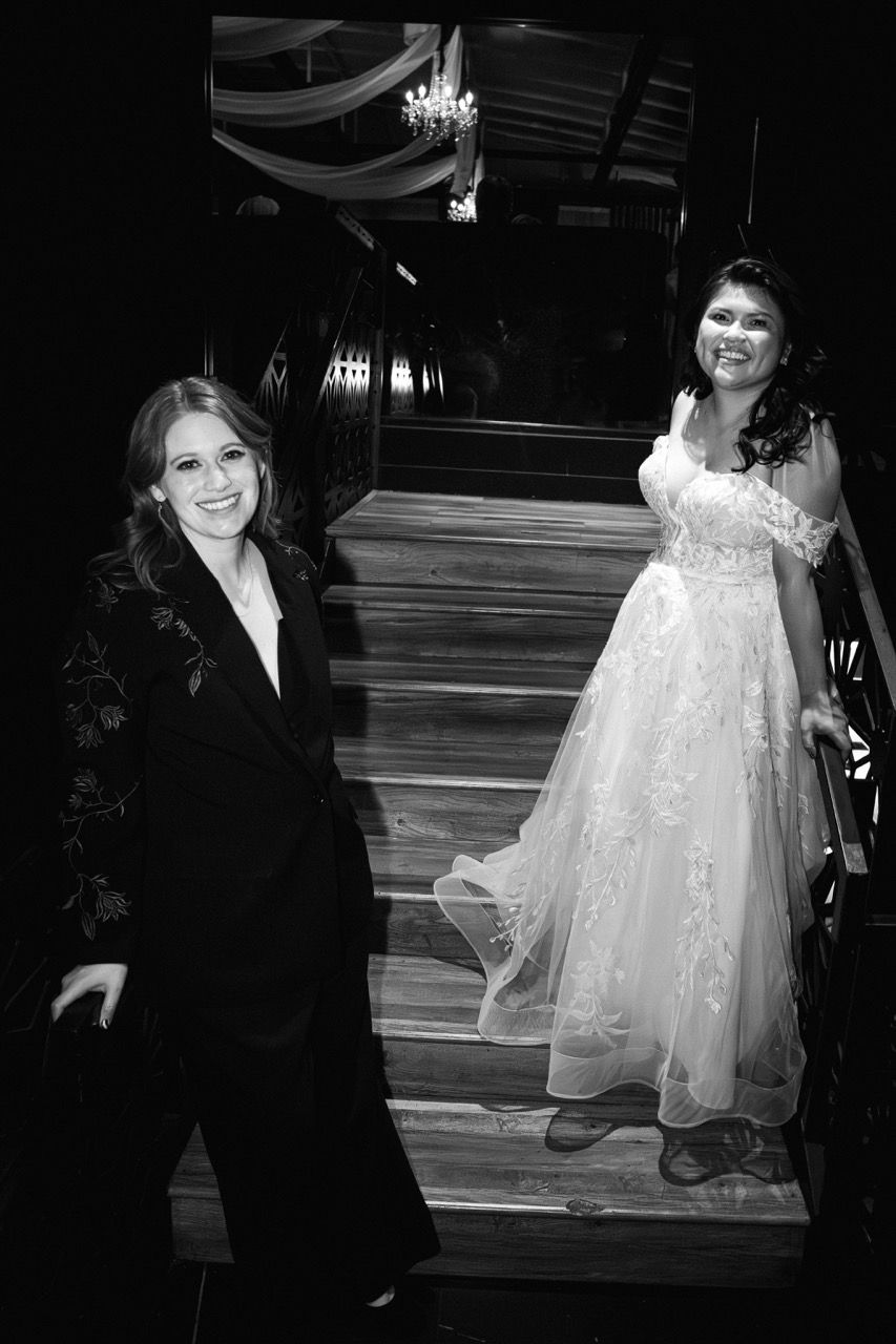 Brides pose on staircase at reception party.