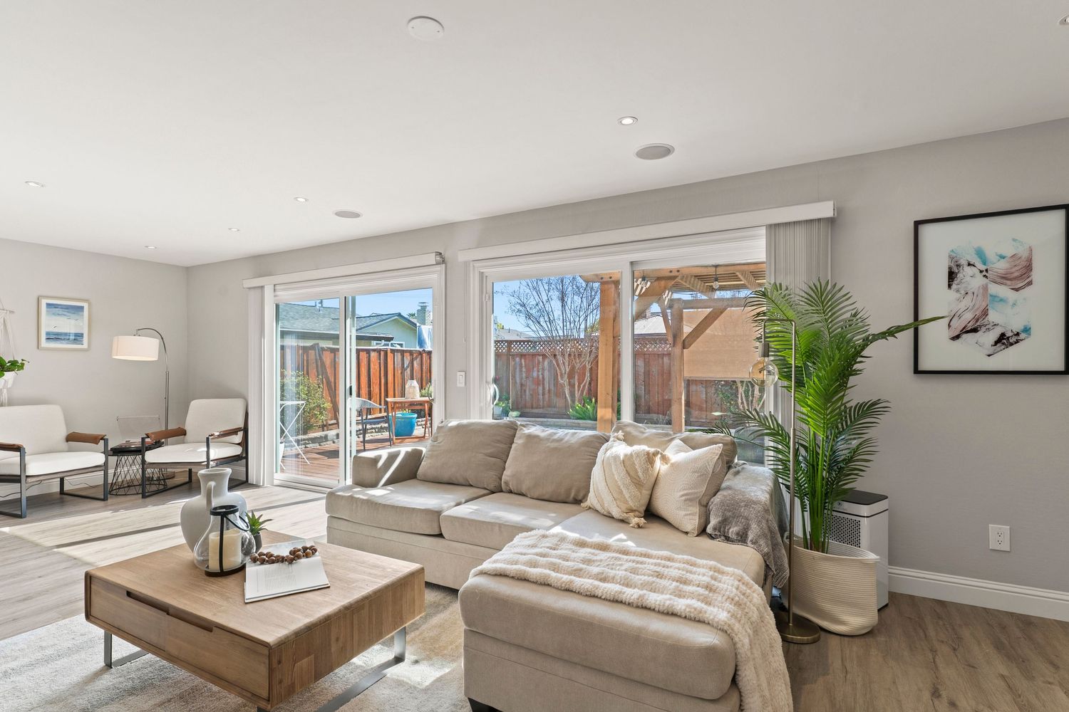 Bright living room with sectional sofa, large windows, hardwood floors, and patio view.