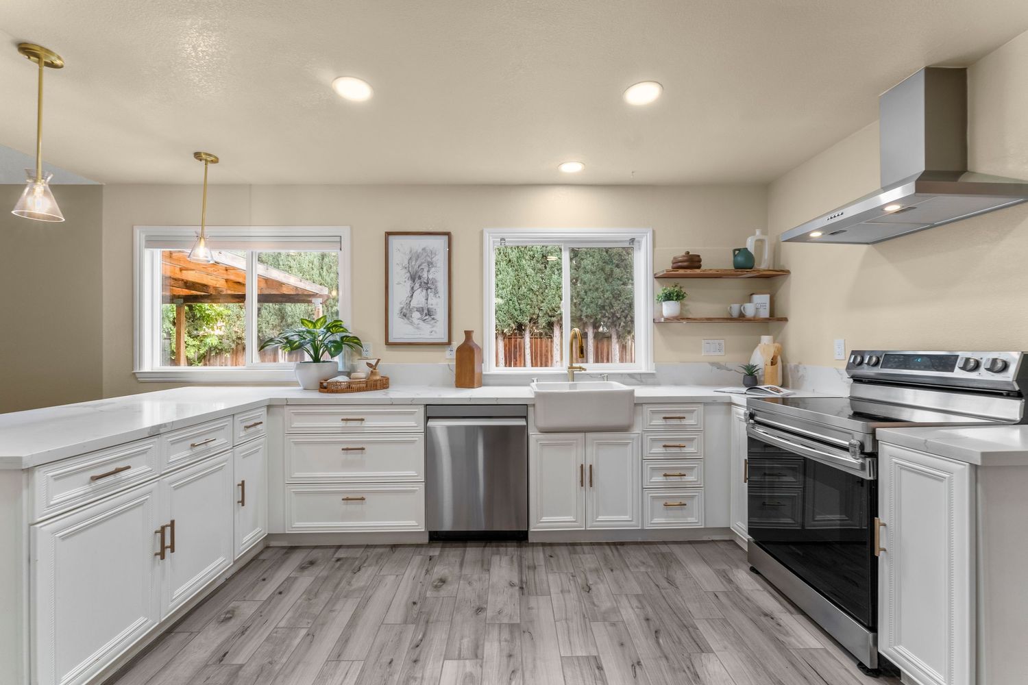 Modern white kitchen with stainless appliances, farmhouse sink, open shelving, and light hardwood floors.