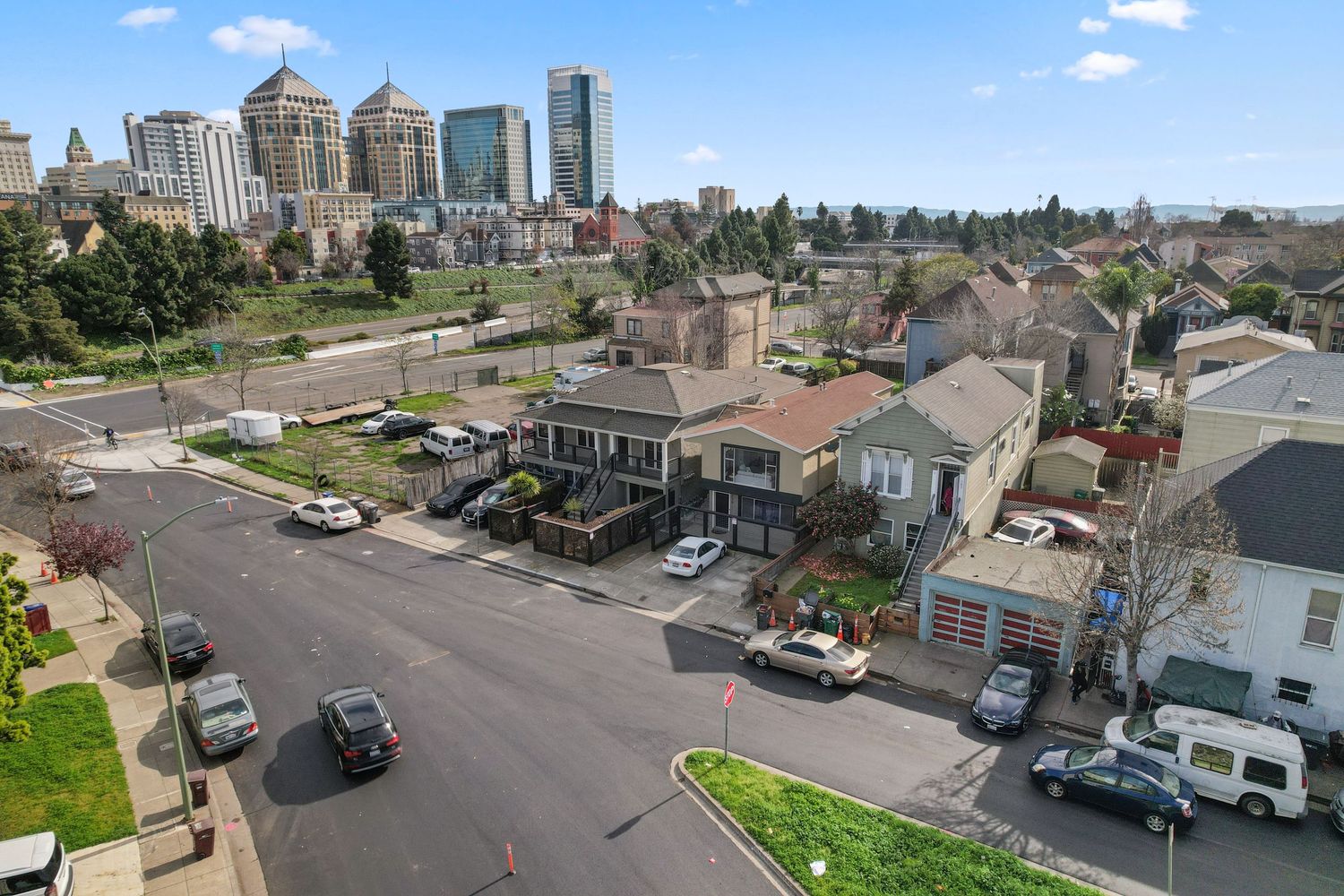 Aerial view of Oakland residential neighborhood with downtown skyline and tree-lined streets.