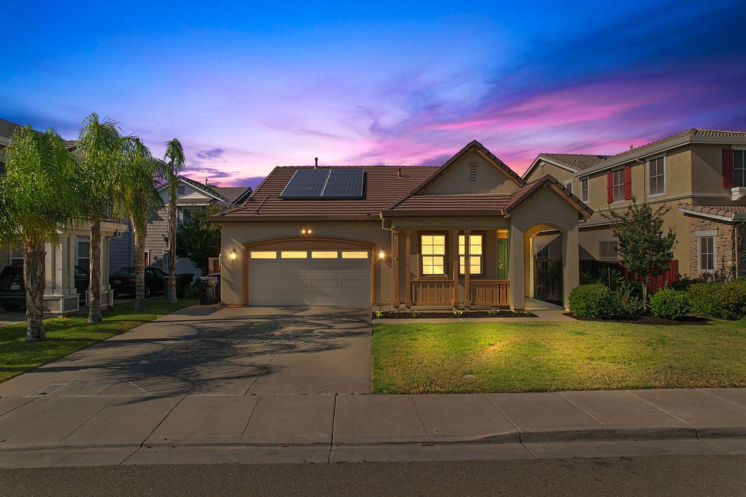 Craftsman home exterior at dusk with solar panels, two-car garage, front porch, and manicured lawn.