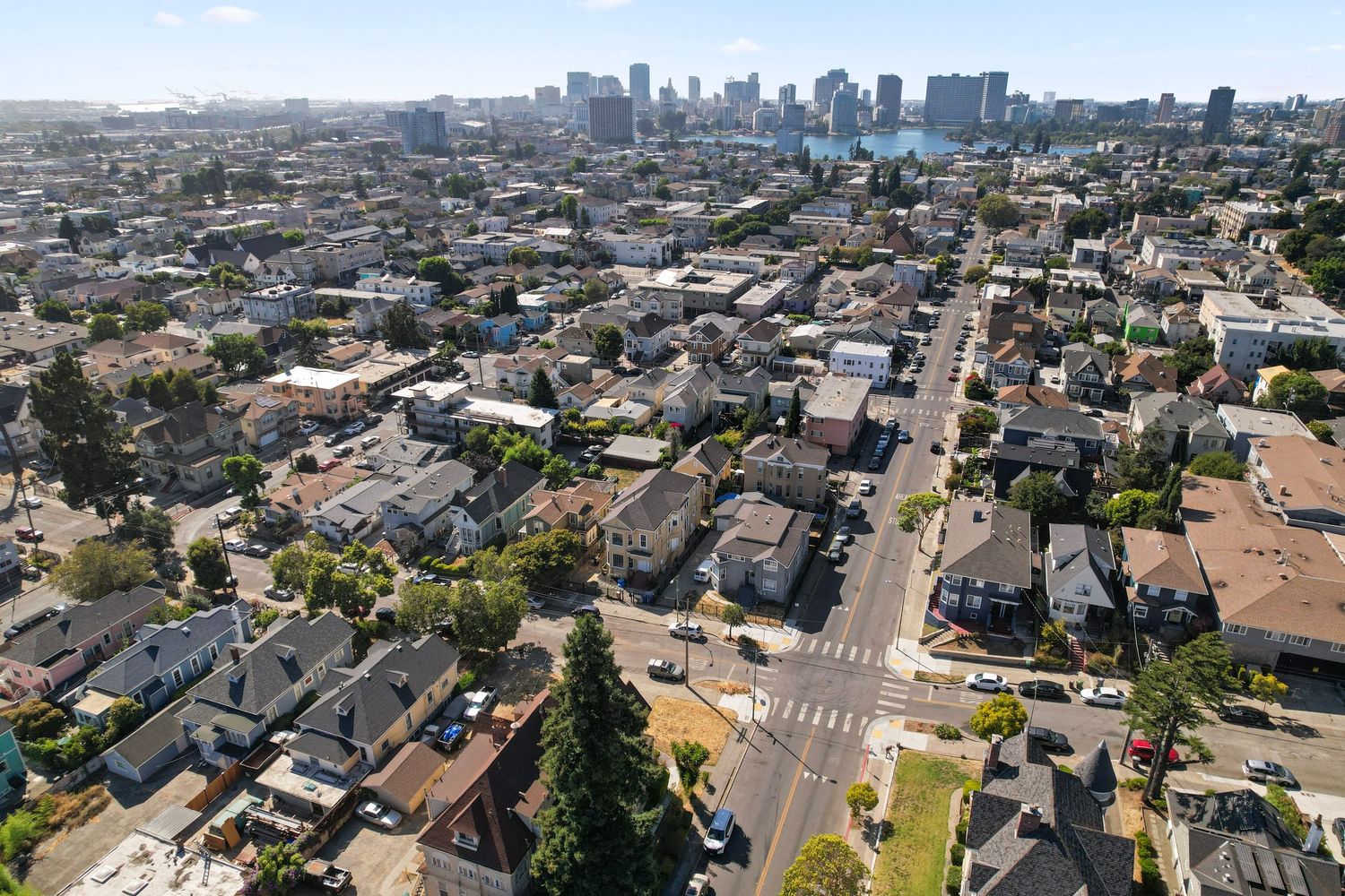 Aerial view of a dense urban residential neighborhood with a city skyline and bay visible in the distance.