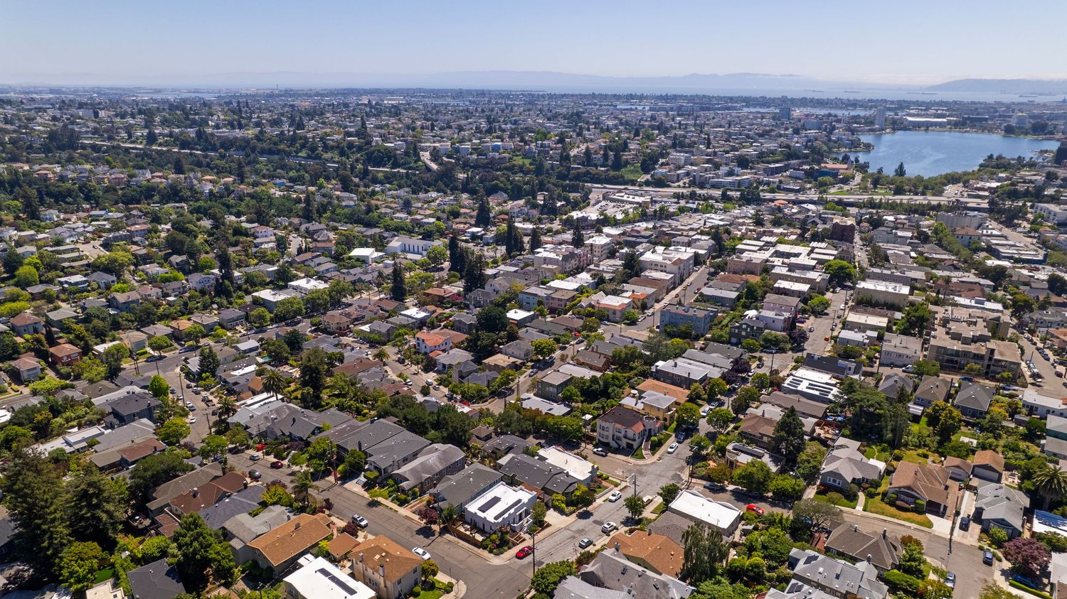 Aerial view of a residential neighborhood with tree-lined streets and a lake visible in the background.