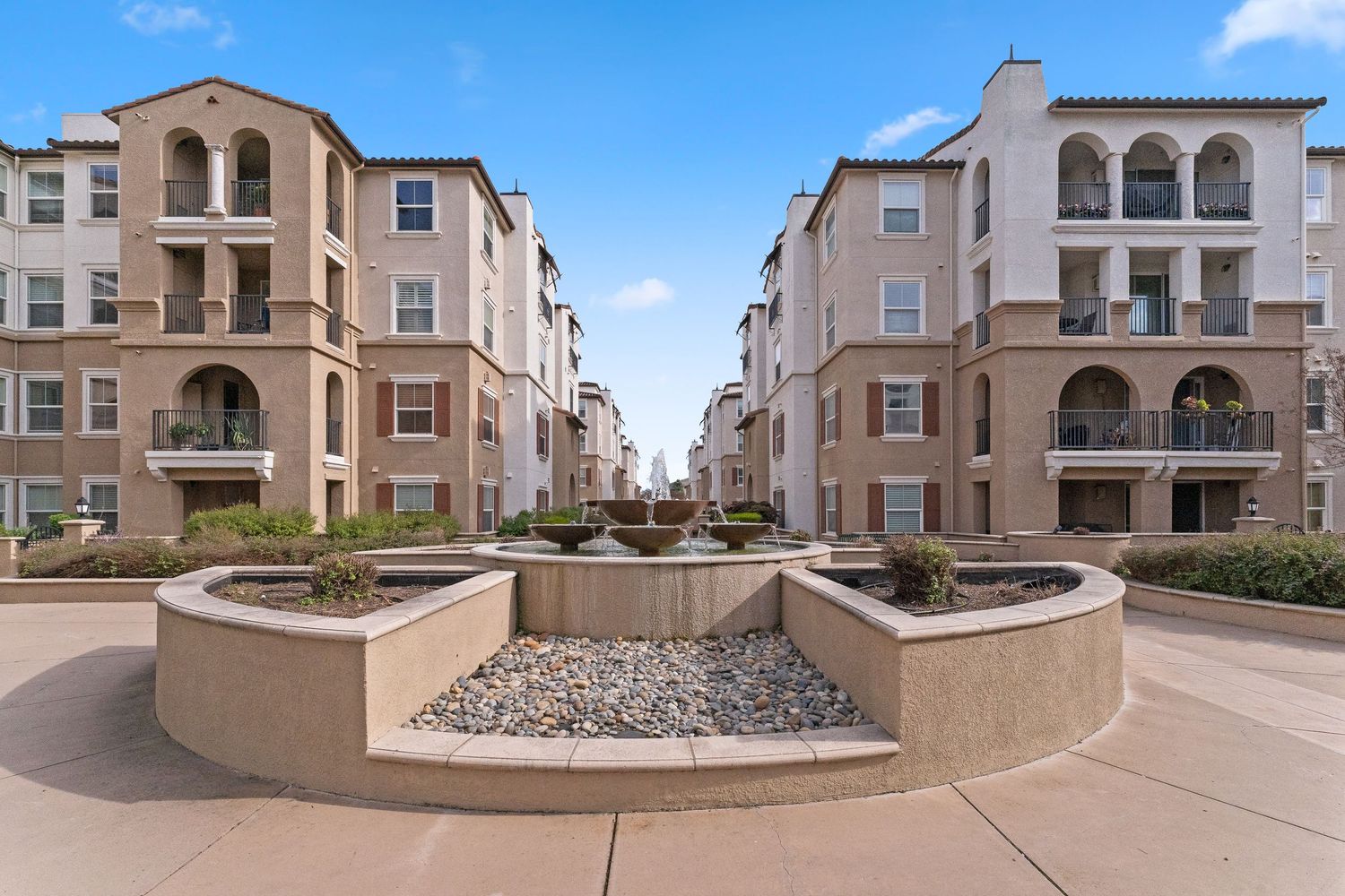 Multi-story residential apartment complex with courtyard fountain and landscaped common area.