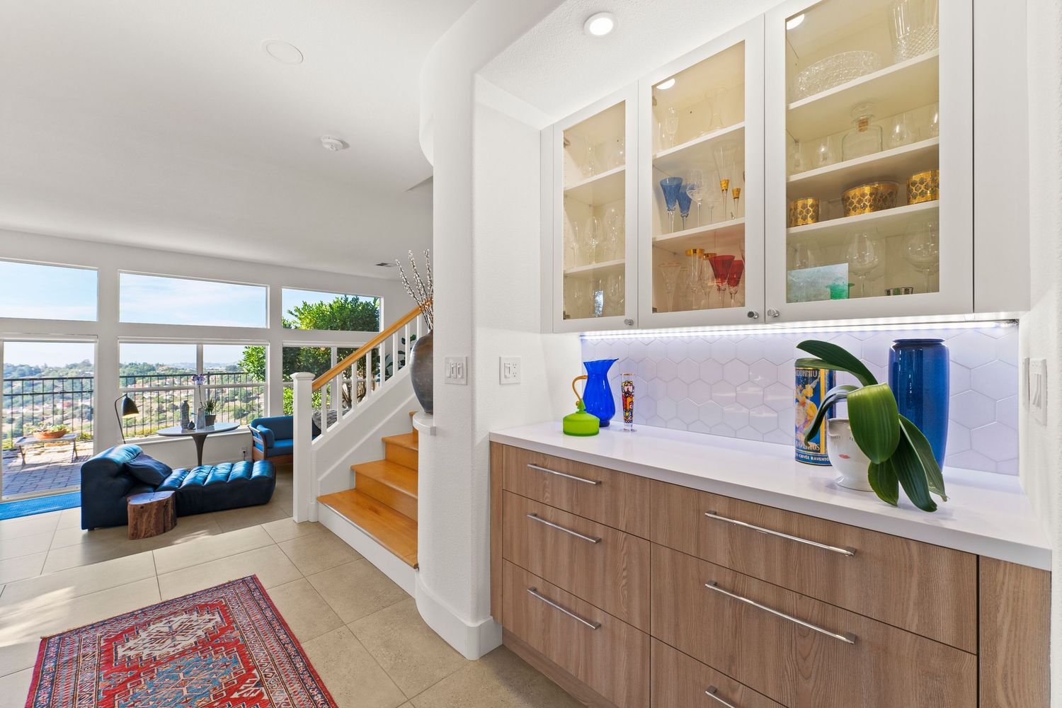 Bright butler pantry with glass-front cabinets, wood drawers, and panoramic city views.