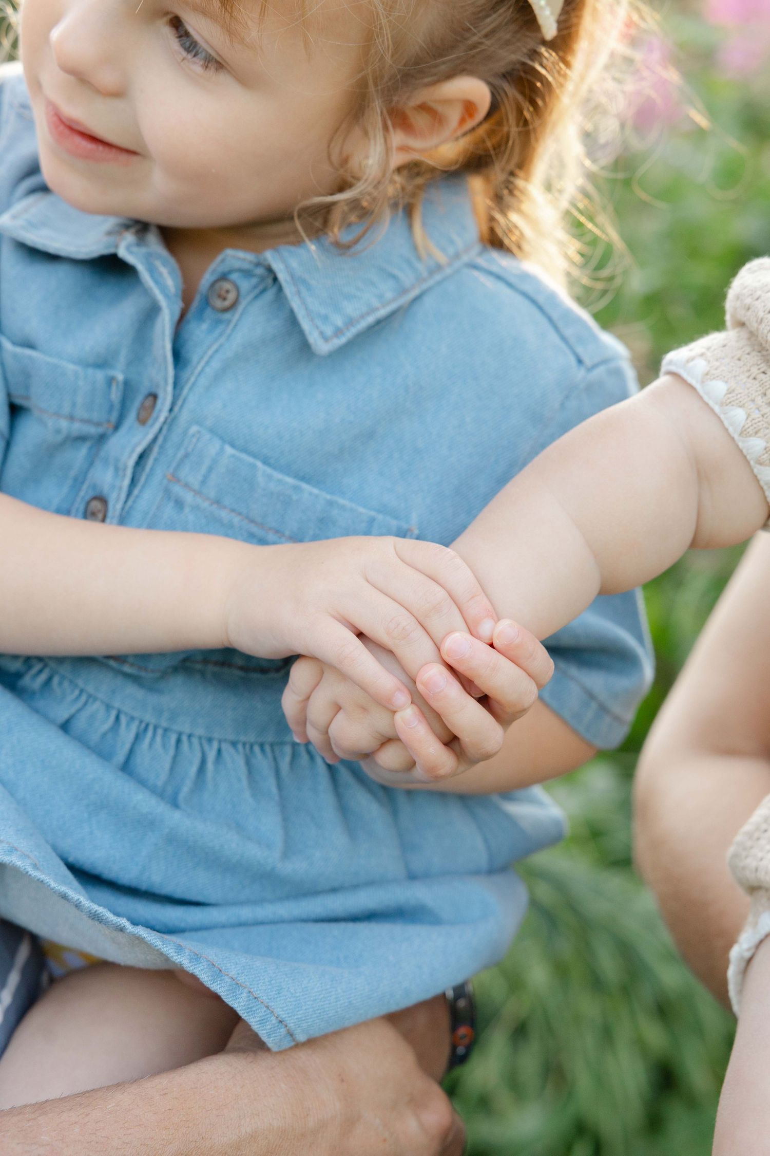 detail photo of a toddler holding her baby brothers hand