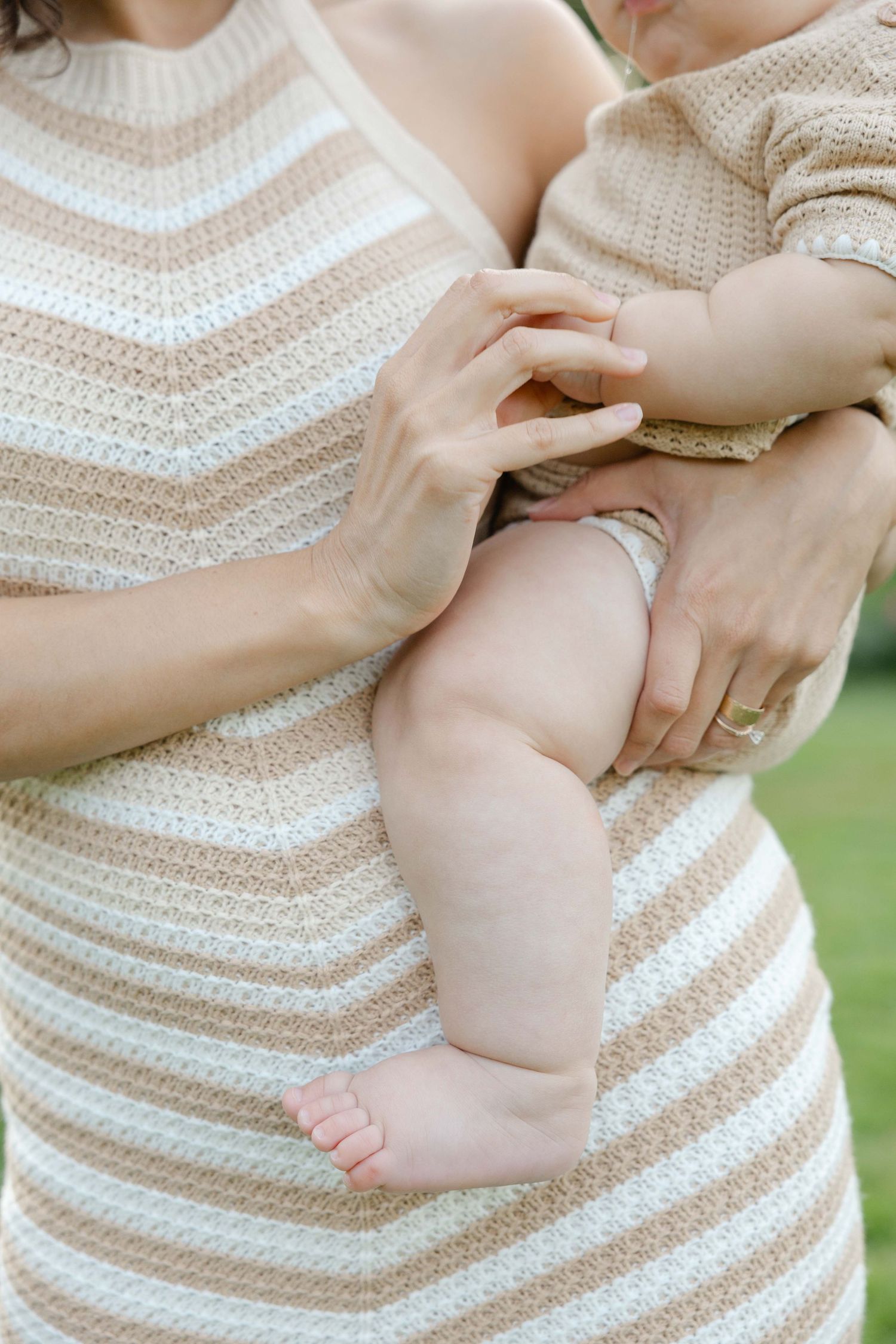 detail photo of a mom holding her baby showing her hands and baby's legs during family session in Apple Valley