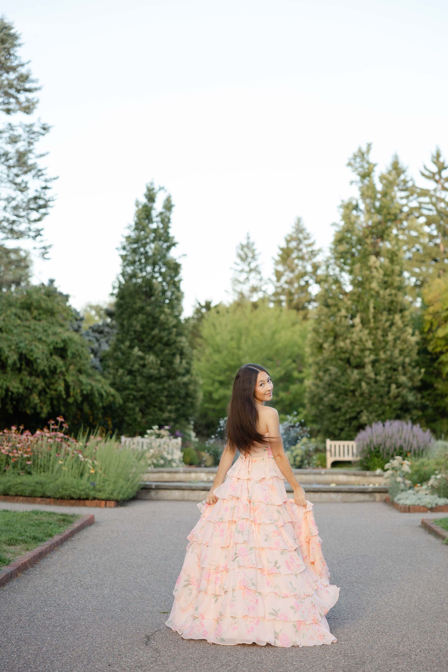 High school senior posing in a flower garden in arboretum Chaska in a long flower dress