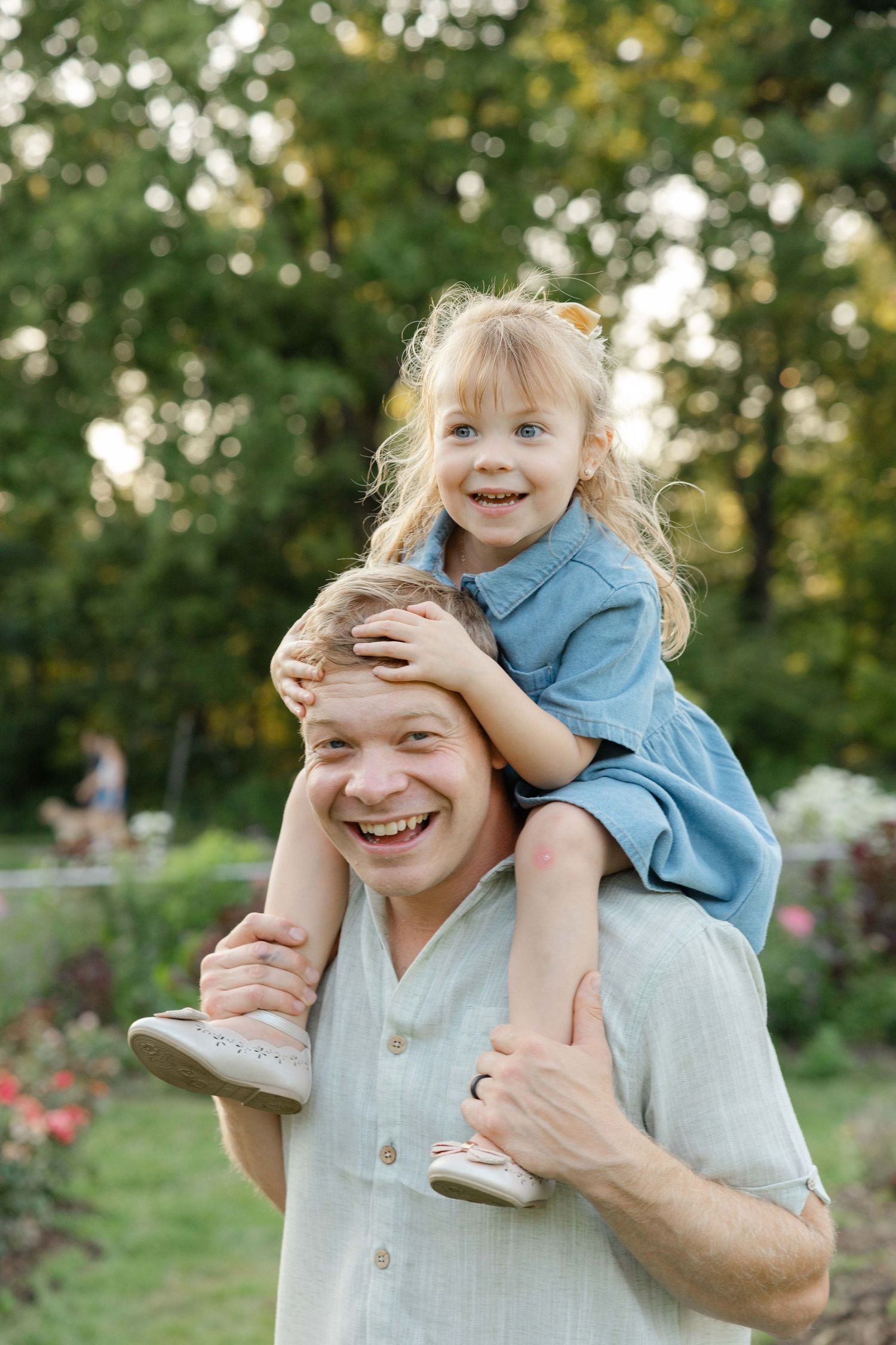 dad holding his toddler on his shoulders, girls is being silly, dad is smiling, in Lakeville, MN