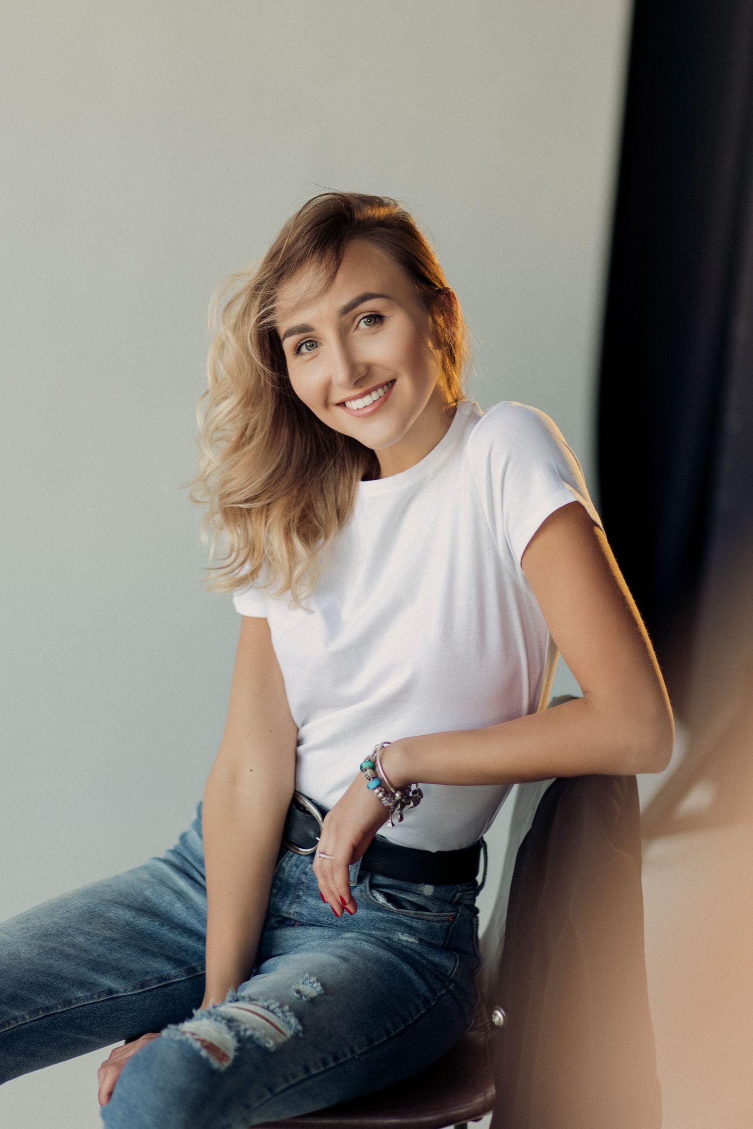 anastasia roberts is a photographer, she's sitting on a chair smiling and looks very pleasant to work with