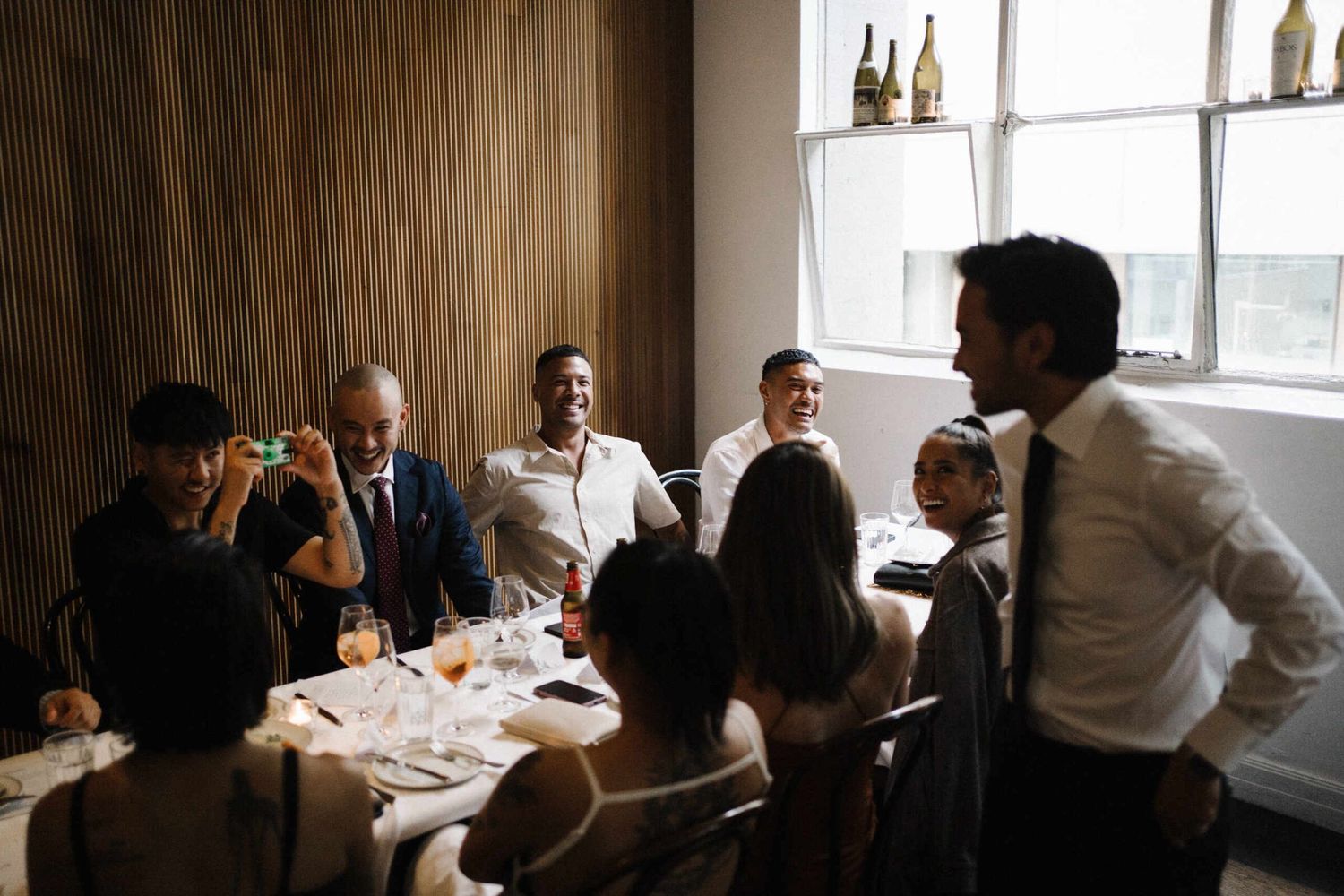 Waverley and Jordan’s wedding at Cumulus Up, Melbourne City. Jordan laughing with his best friends at the table. Such a joyful moment.