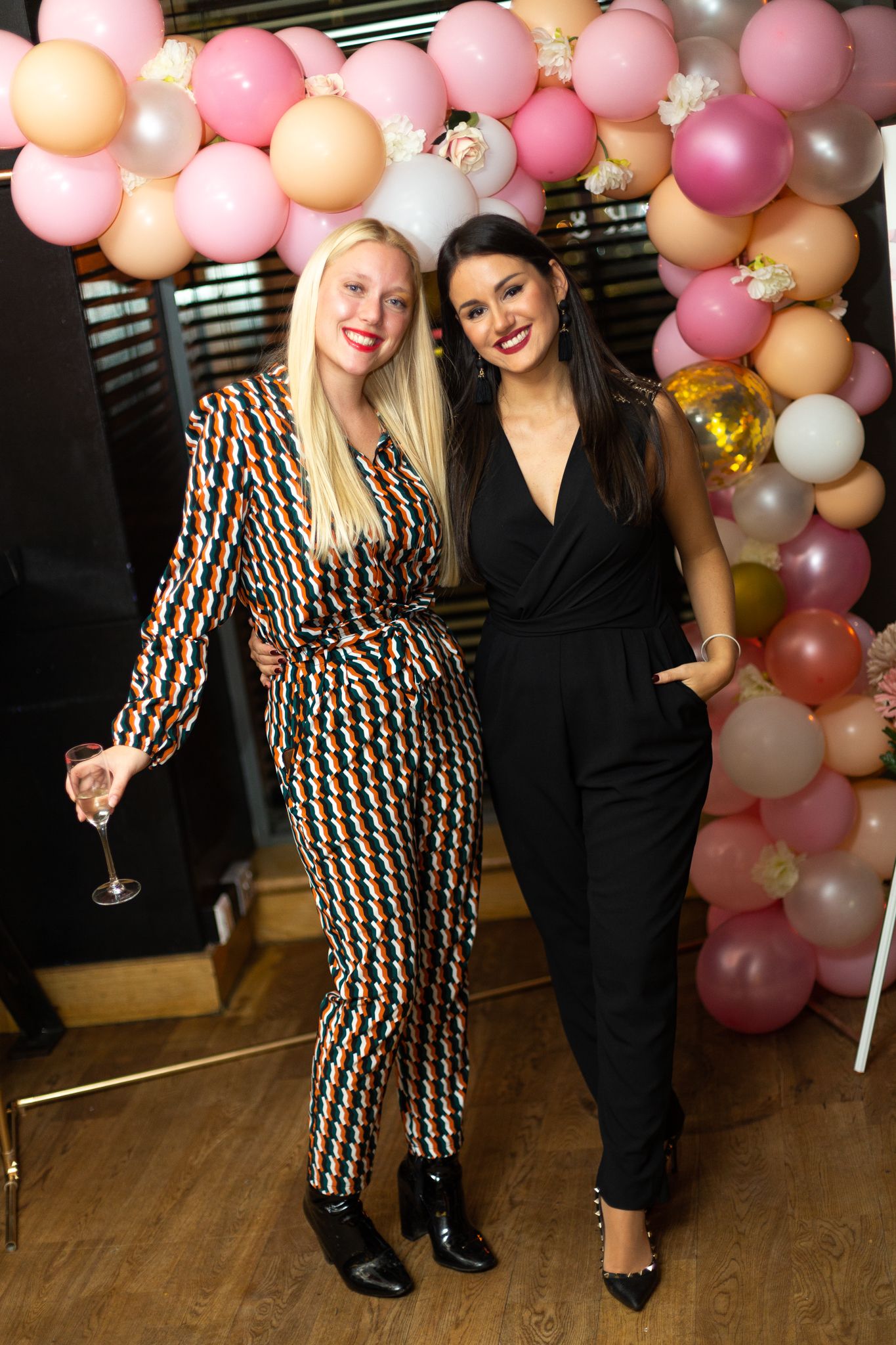 two young attractive women blond and brunette enjoying an evening out having a drink