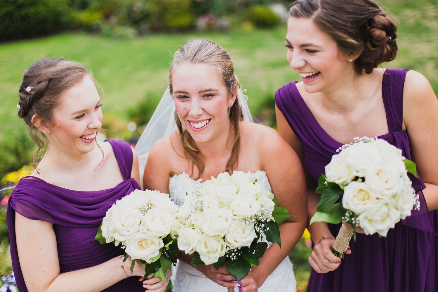 bride and her bridesmaids laughing together while holding their bouquets