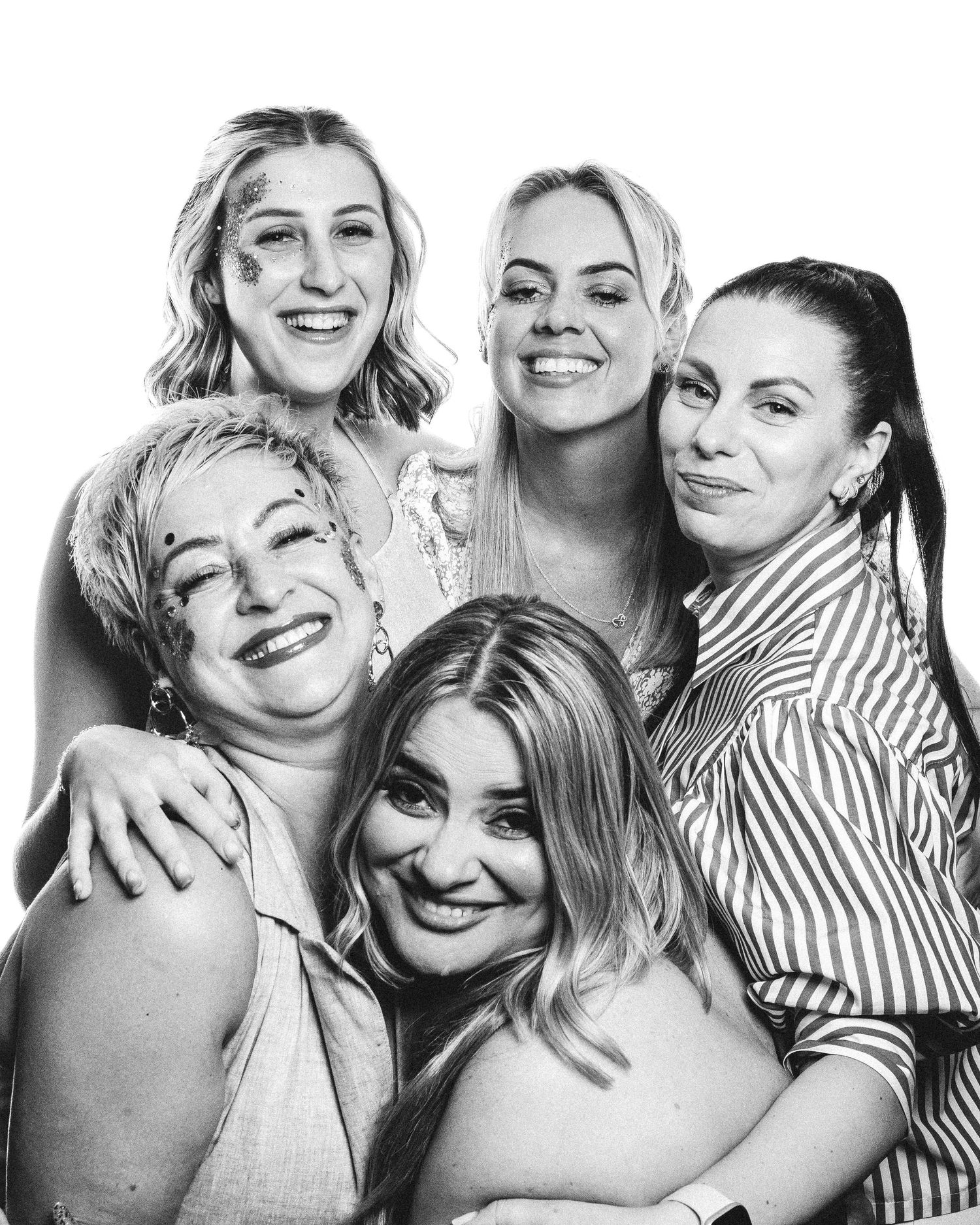 Black and white portrait of five friends smiling and embracing while posing together in casual attire.