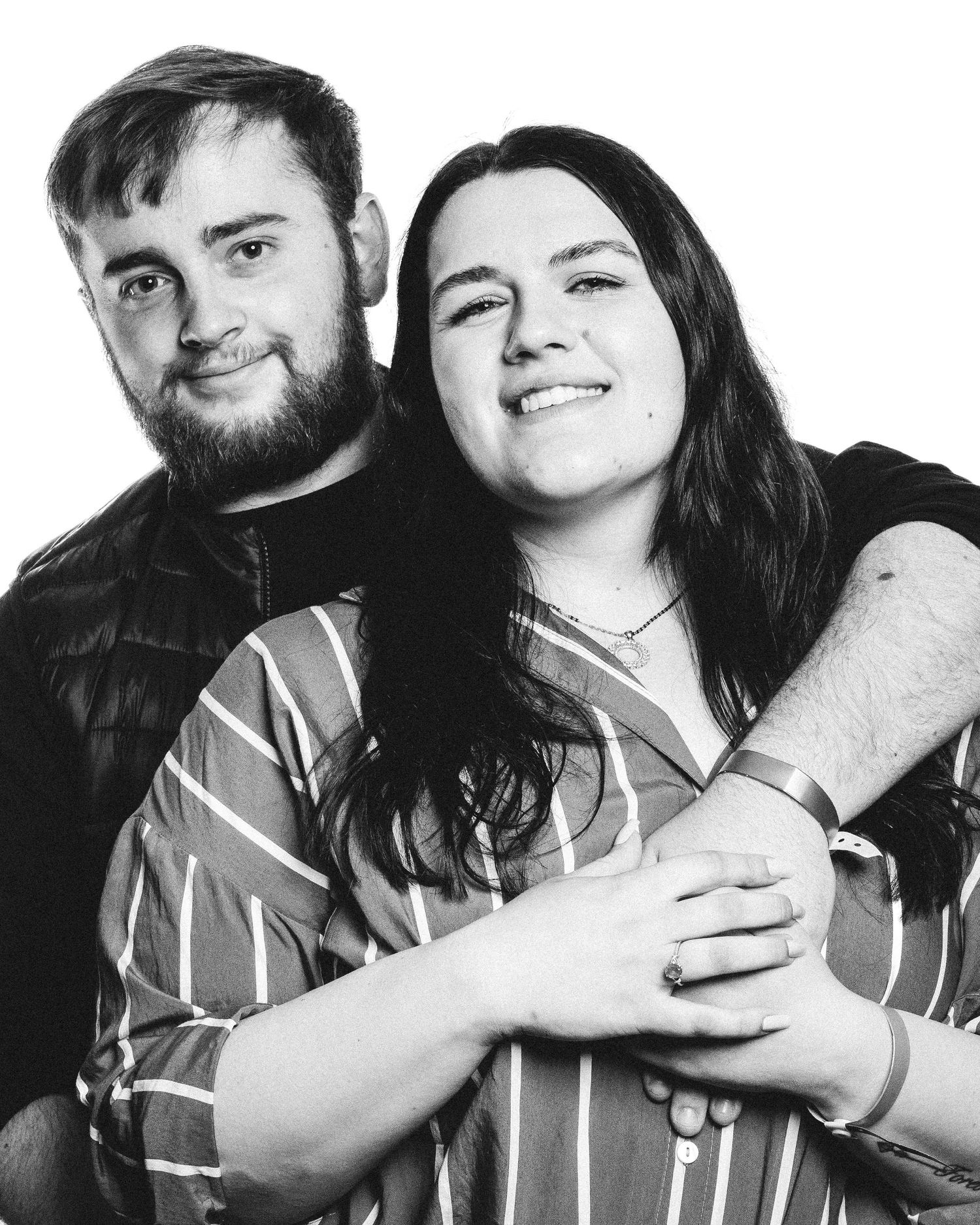 A joyful black and white portrait of two people embracing and smiling at the camera.