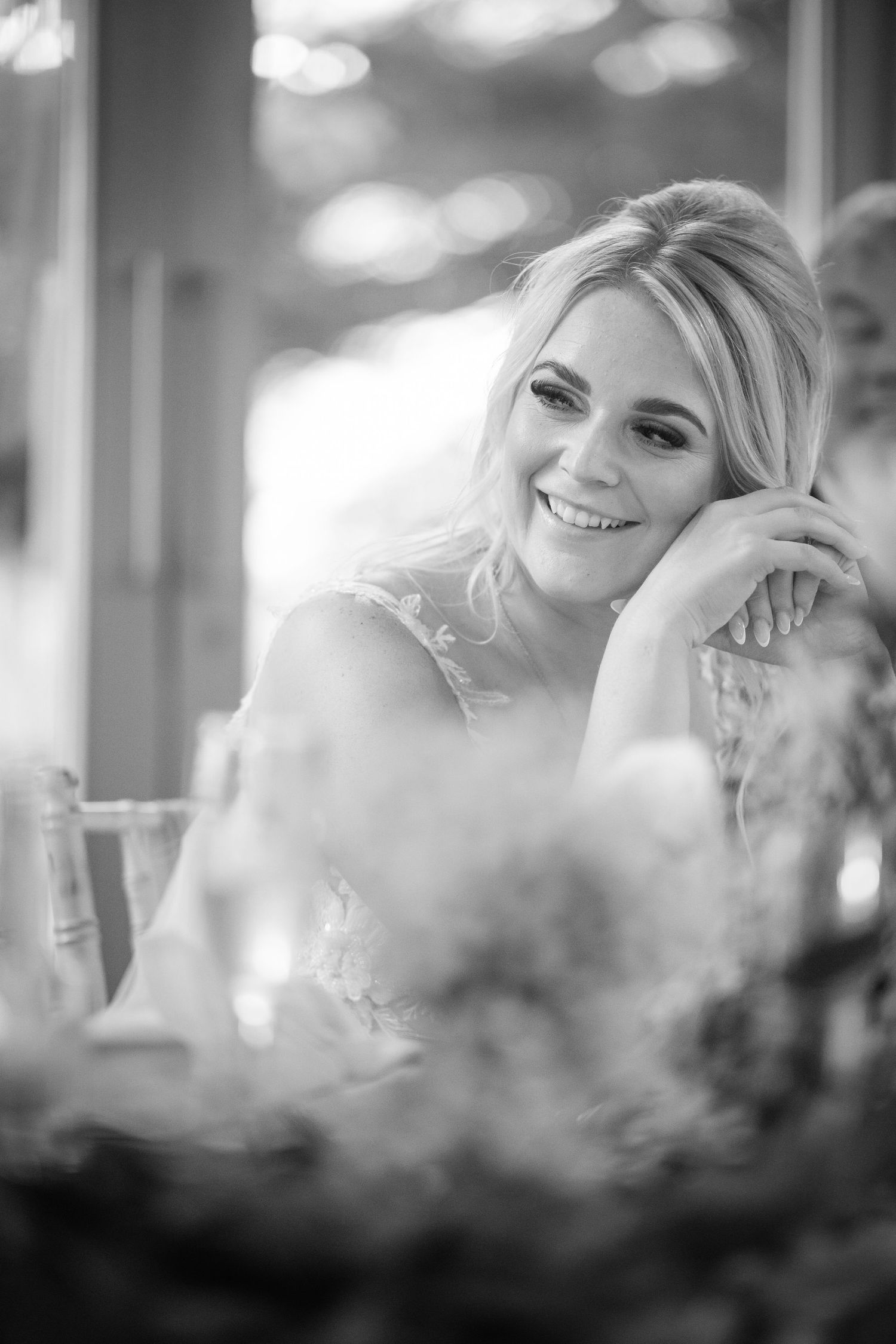 A black and white candid photograph of a happy bride on her wedding day with soft bokeh effects in the background.