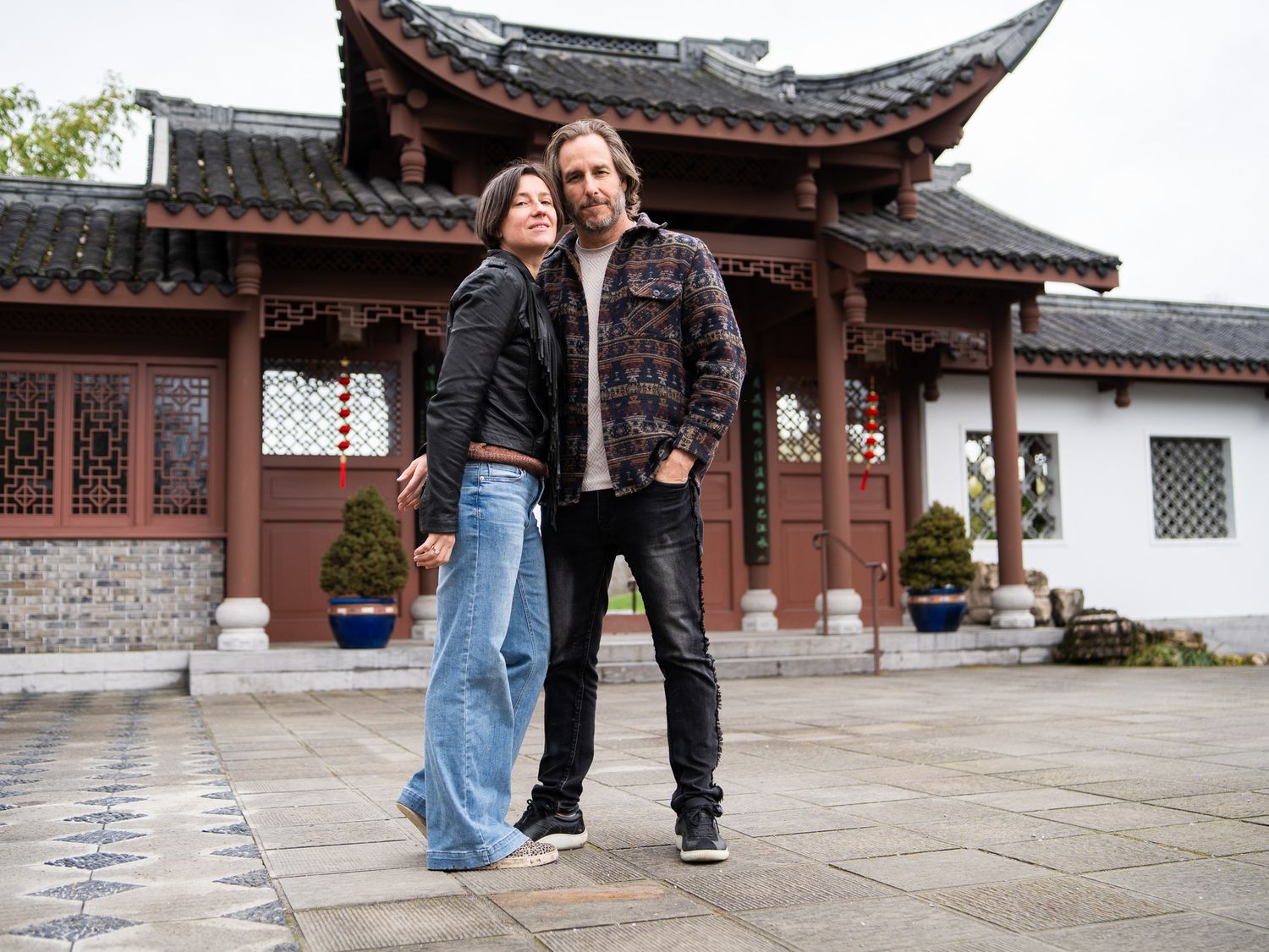 Couple posing together in front of a traditional Chinese pagoda building on a stone courtyard.
