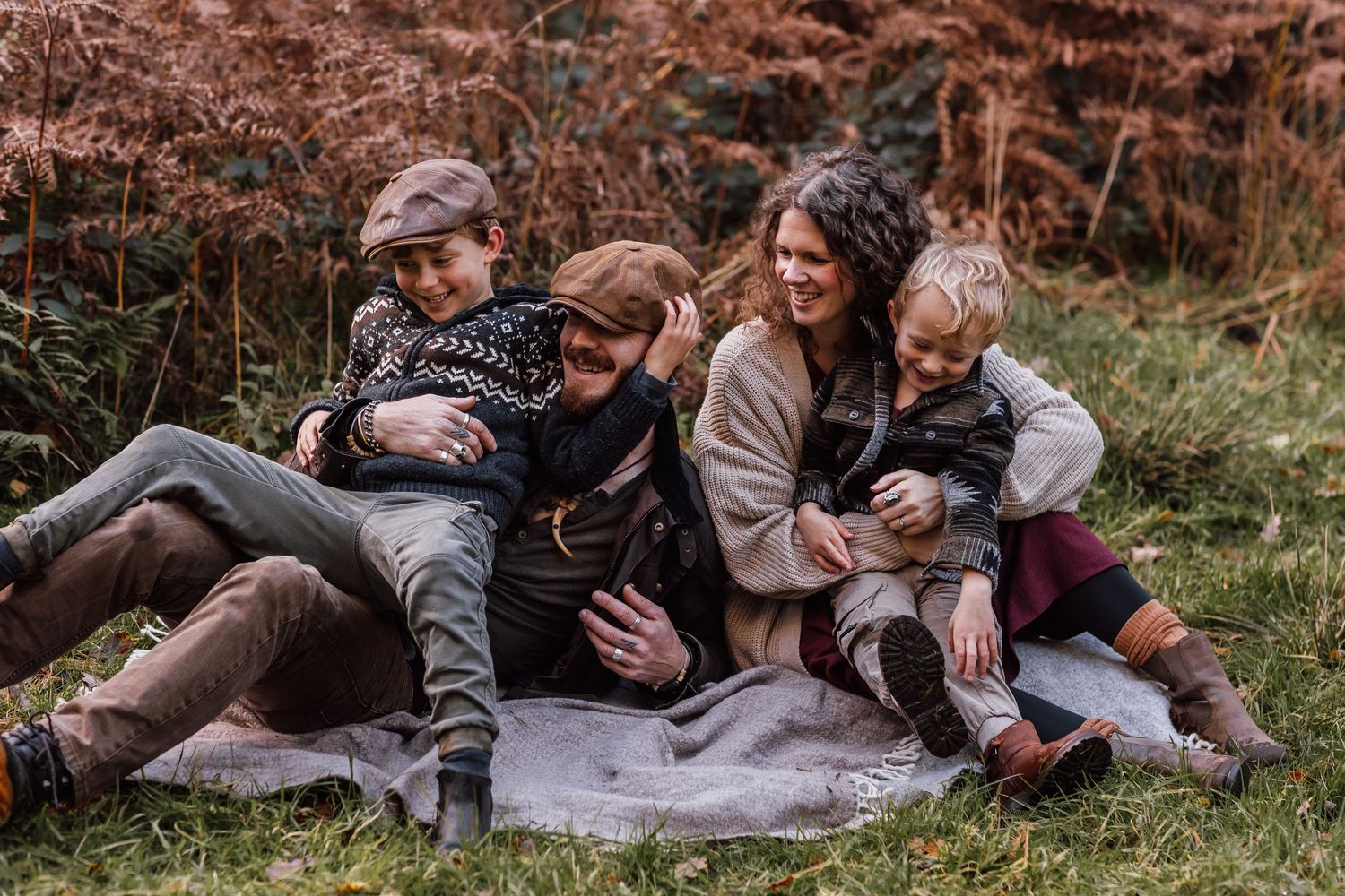 Family members lying on a blanket in autumn grass sharing tender moments together in a series of candid shots.