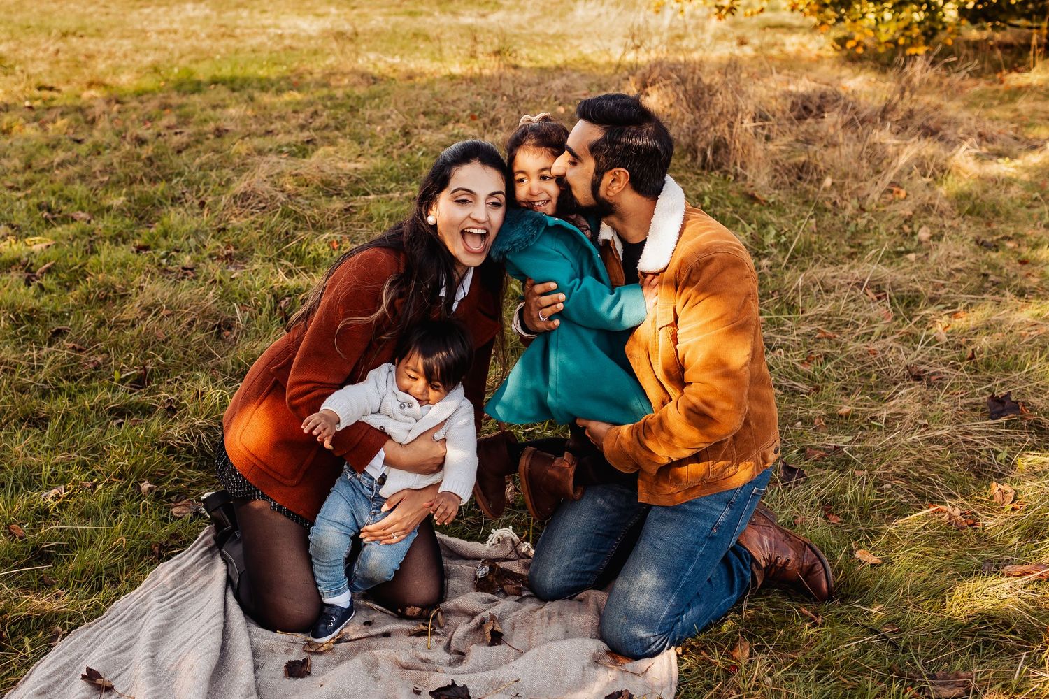 Group enjoys a cozy autumn picnic on a blanket in golden field during sunset.