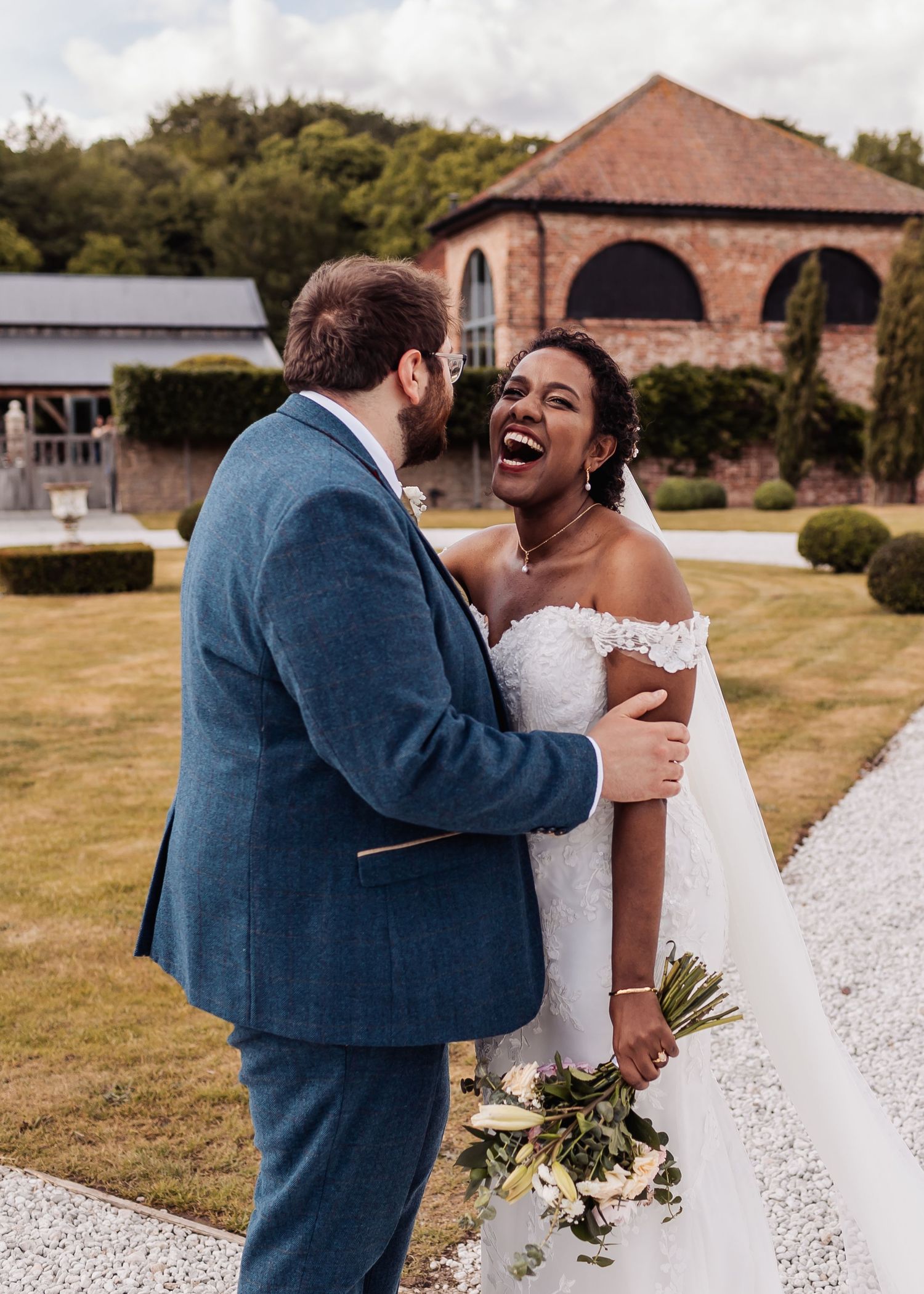 A joyful couple shares a candid moment of laughter together outdoors near a brick building.