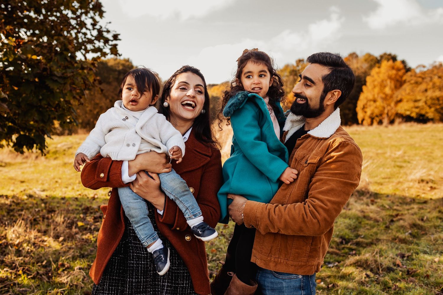 A family enjoys an autumn day outdoors with fall foliage and golden colors in the background.