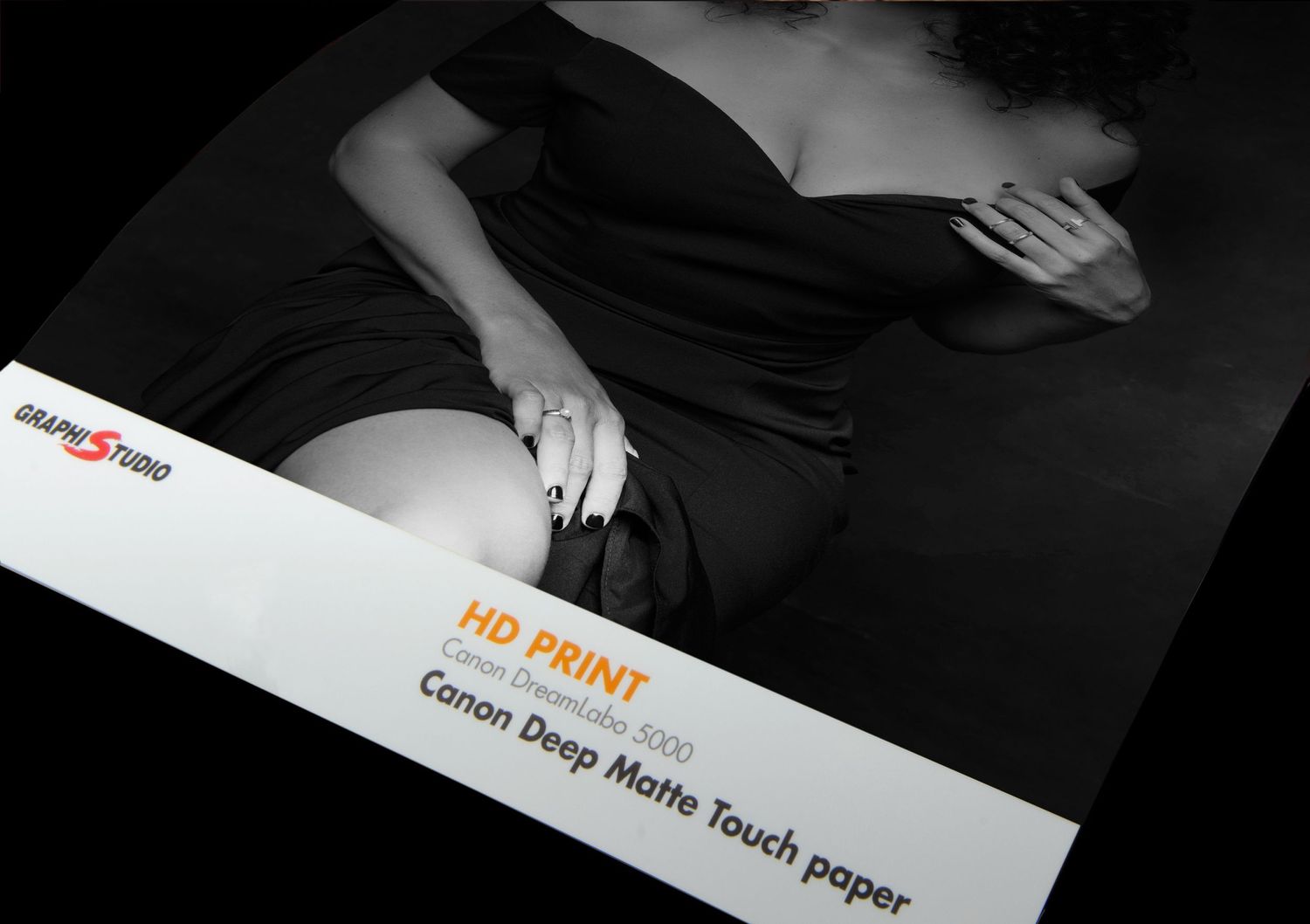 Black and white photo showing HD print matte touch paper product marketing display against dark background.