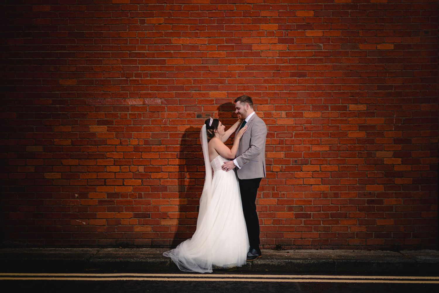 Newlyweds share romantic moments against rustic brick walls during their wedding photoshoot.