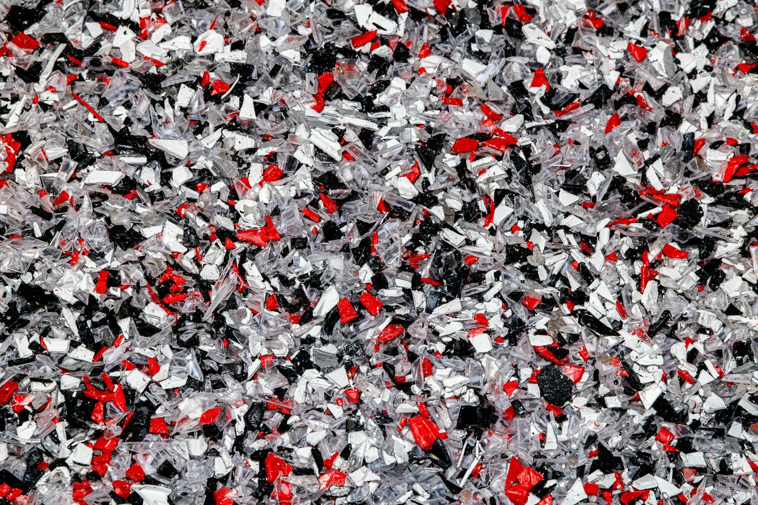 Abstract pattern of black, white, and red confetti-like shapes scattered across a scattered mosaic background.