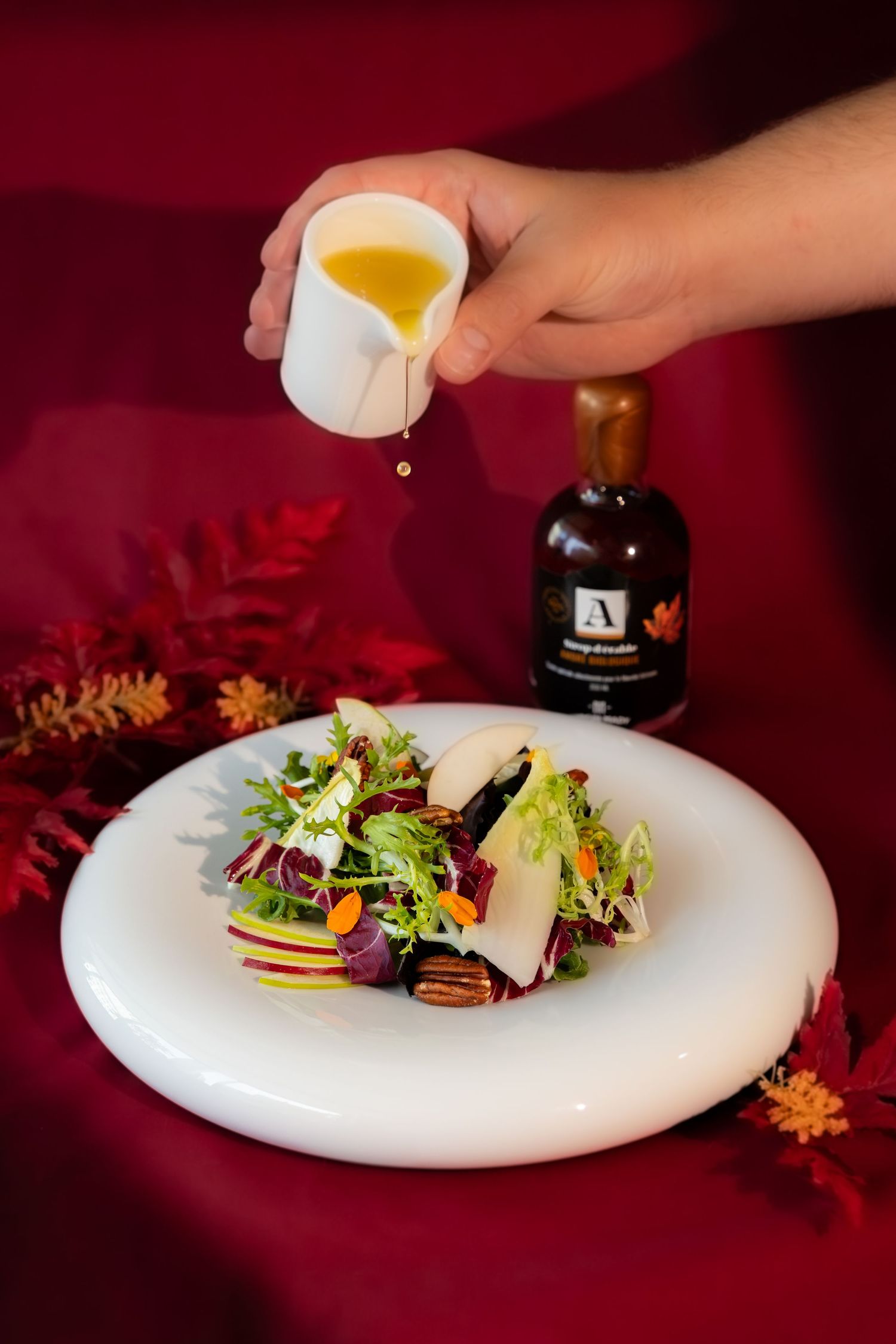 A sequence showing salad plating and dressing being added to a white plate against a dark red background.
