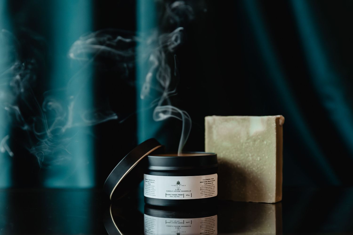 Artisanal soap and product packaging with smoke effect against dark background.